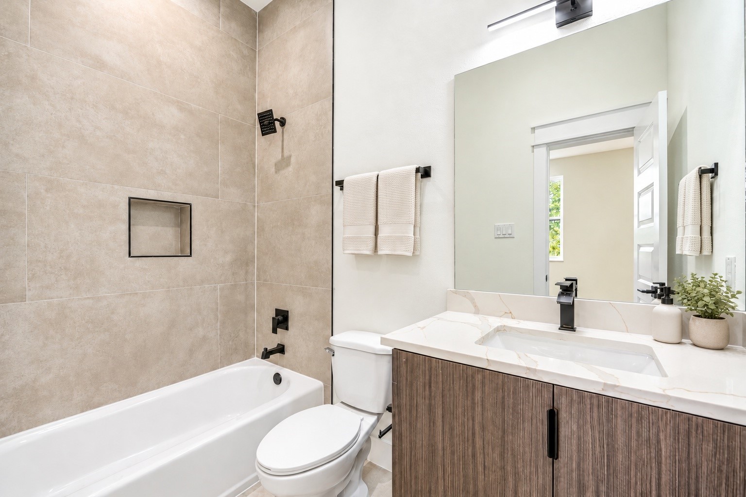 Third-floor ensuite full bath highlighting a clean white vanity, a clear view of the matte black plumbing fixtures, and floor-to-ceiling tile work over the tub.