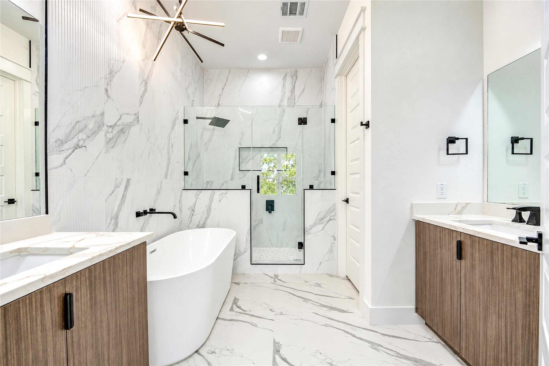 Primary bath with a freestanding tub, glass-enclosed rain shower, and vanity with a makeup area.
