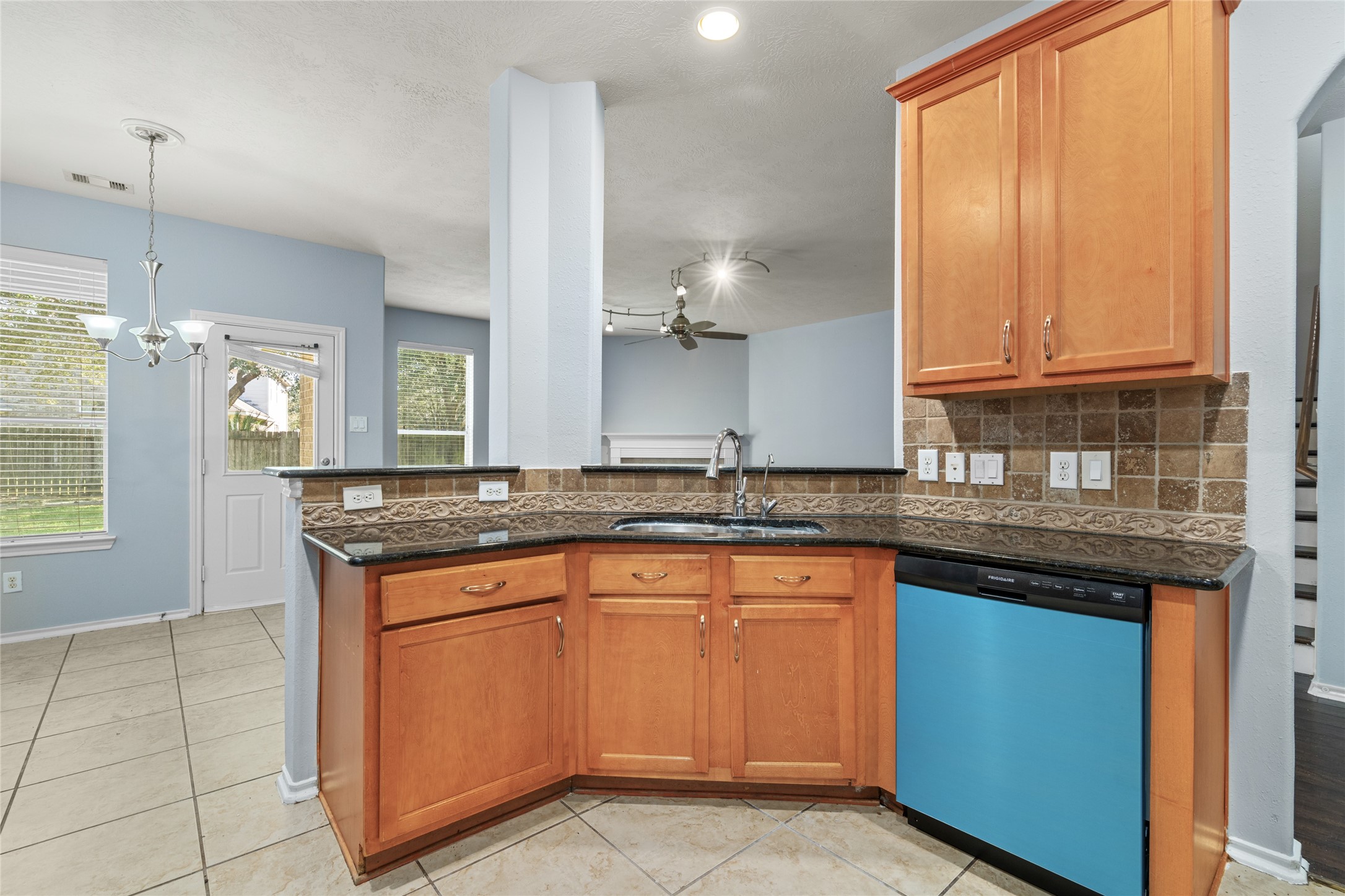 Kitchen corner featuring wraparound granite countertops, wood cabinetry, and a broad work surface. The layout provides room for meal preparation while maintaining an open connection to the surrounding living and dining areas.