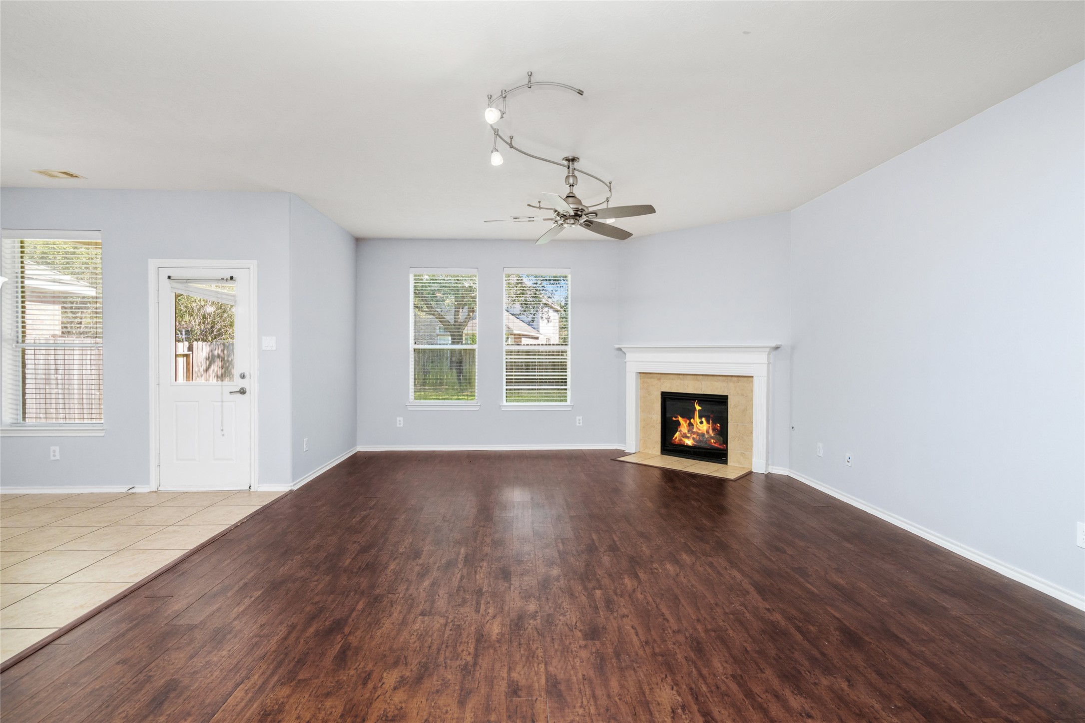Unfurnished living room highlighting its spacious footprint, wood flooring, fireplace, and natural light. Buyers can envision different furniture arrangements while enjoying a central gathering area with room to spread out.