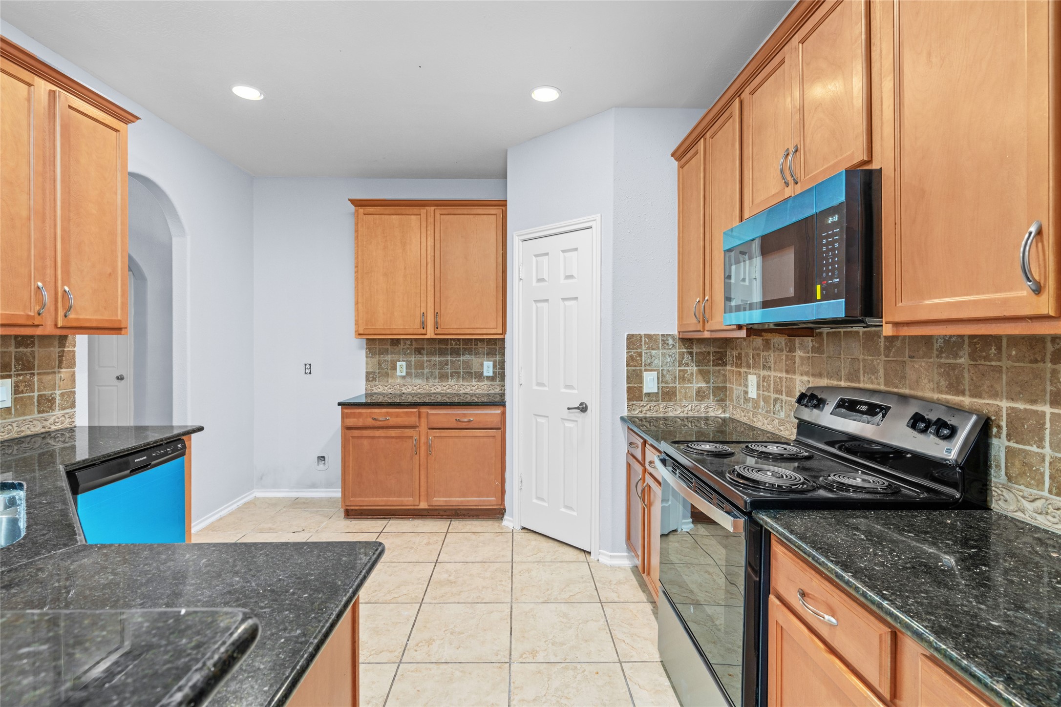Functional kitchen with wood cabinetry, black granite countertops, tiled flooring, and built-in appliances. The arrangement offers substantial cabinet storage and counter space for everyday cooking and meal preparation. Functional kitchen with wood cabinetry, black granite countertops, tiled flooring, and built-in appliances. The arrangement offers substantial cabinet storage and counter space for everyday cooking and meal preparation.