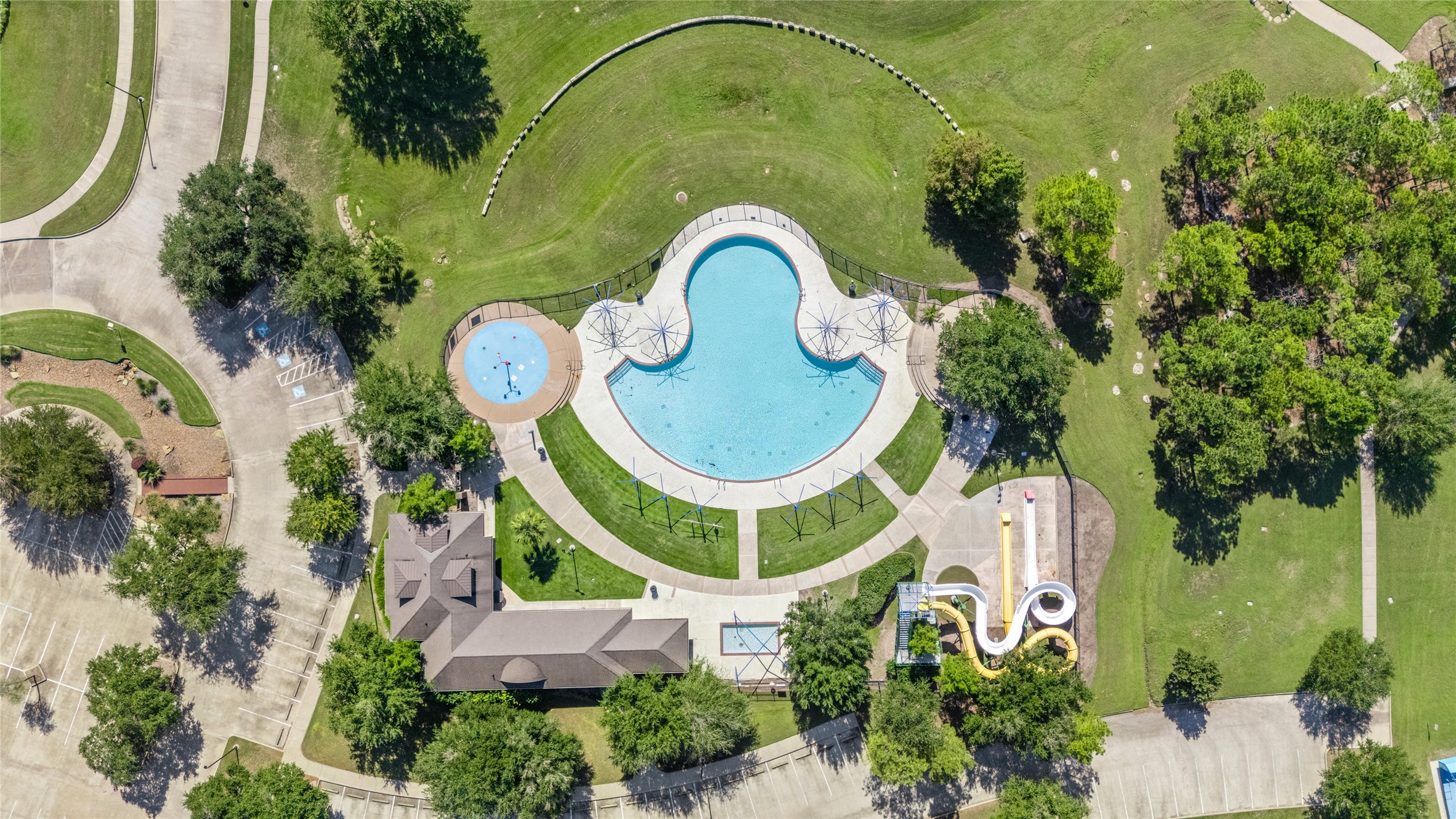 Aerial view of the community swimming pool and landscaped common areas, showcasing the pool's distinctive shape and surrounding recreation space. The shared amenity provides another option for leisure and outdoor enjoyment close to home.