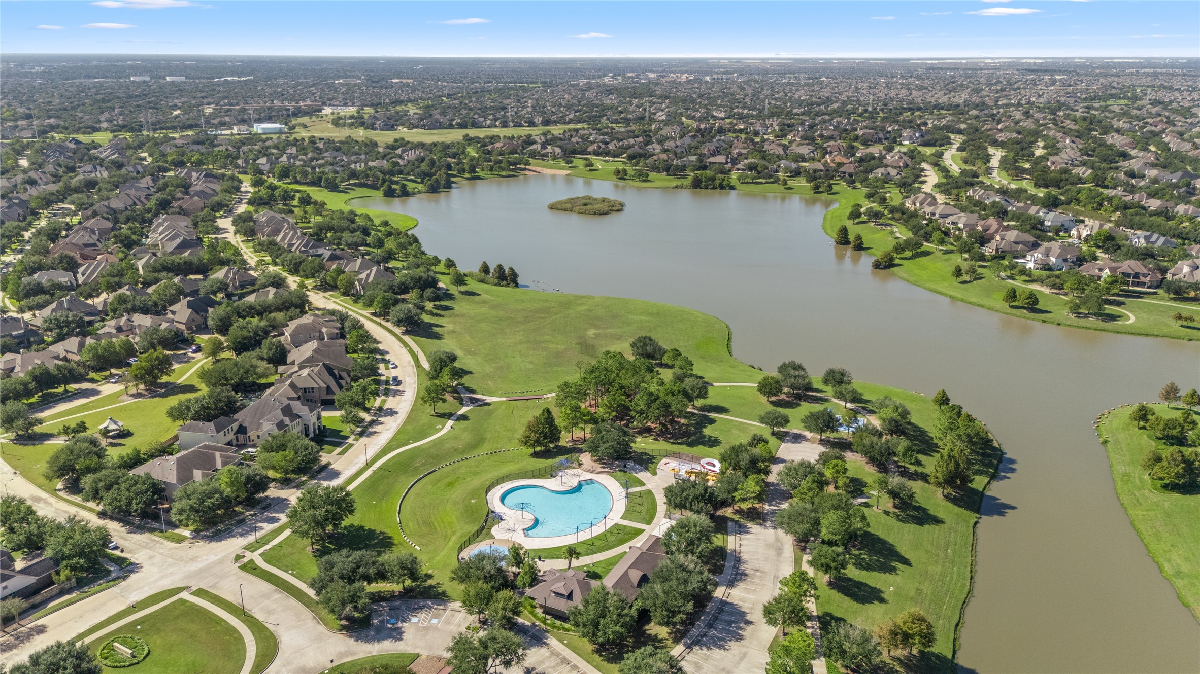 Aerial view of the surrounding community featuring a lake, green spaces, walking areas, and a neighborhood pool. These shared outdoor amenities offer additional opportunities for recreation and enjoying the surrounding community. Aerial view of the surrounding community featuring a lake, green spaces, walking areas, and a neighborhood pool. These shared outdoor amenities offer additional opportunities for recreation and enjoying the surrounding community.