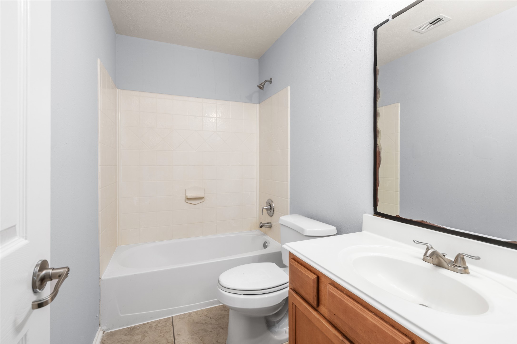 Secondary bathroom featuring a tub-and-shower combination, vanity storage, and neutral finishes. The practical layout serves bedrooms and household members with a convenient option for both bathing and daily routines.