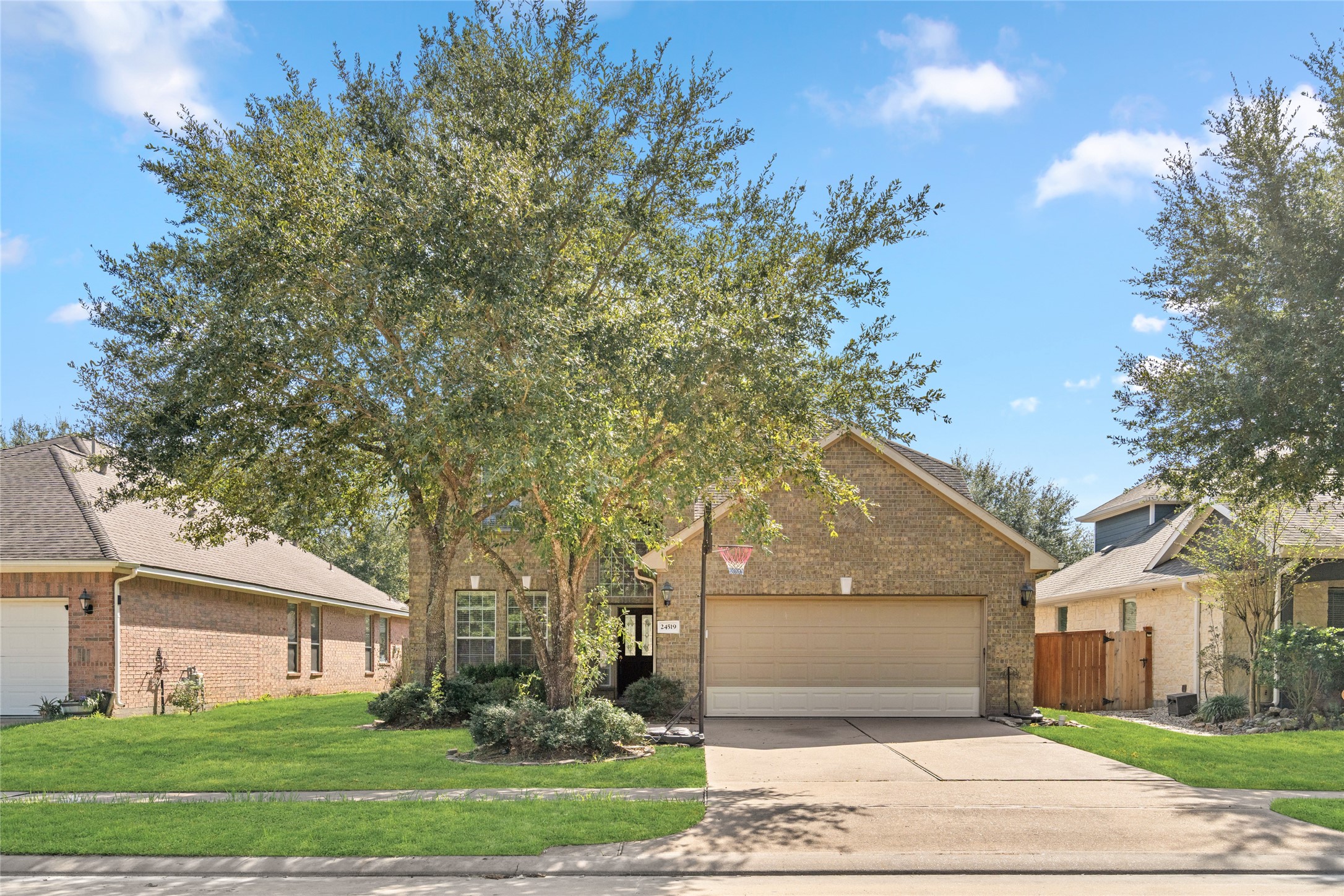 Inviting front exterior with a two-car garage, mature shade tree, and a well-kept lawn. The established landscaping adds character while creating a pleasant setting for everyday living.