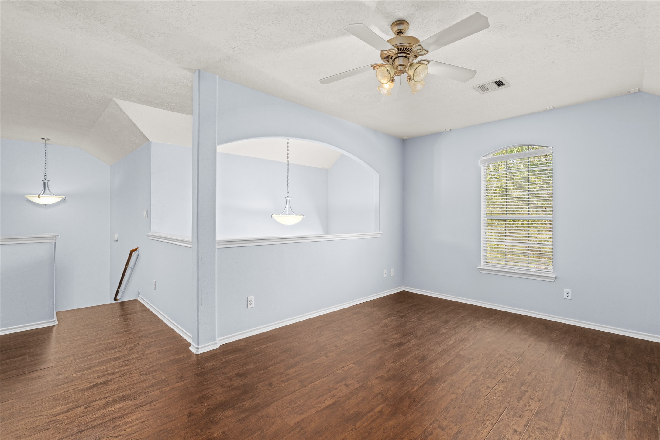 Open second-floor game room with wood flooring, a ceiling fan, and an expansive layout. The flexible space can serve as a recreation room, hobby area, or additional lounge, giving the household room to enjoy separate activities.