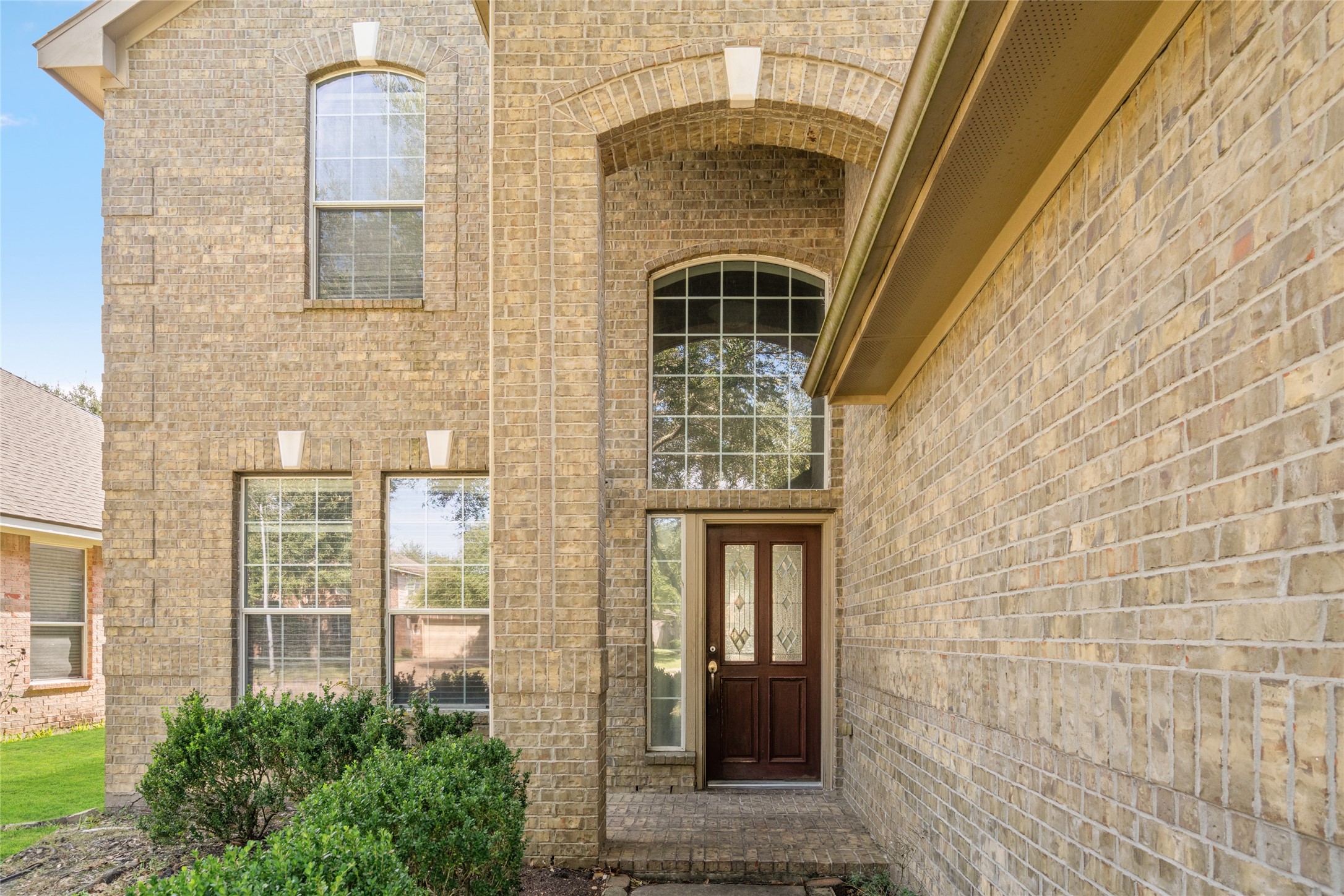 Grand arched entry with tall windows and a covered front doorway, showcasing the home's architectural character. The elevated entry and natural light create a welcoming transition into the interior.