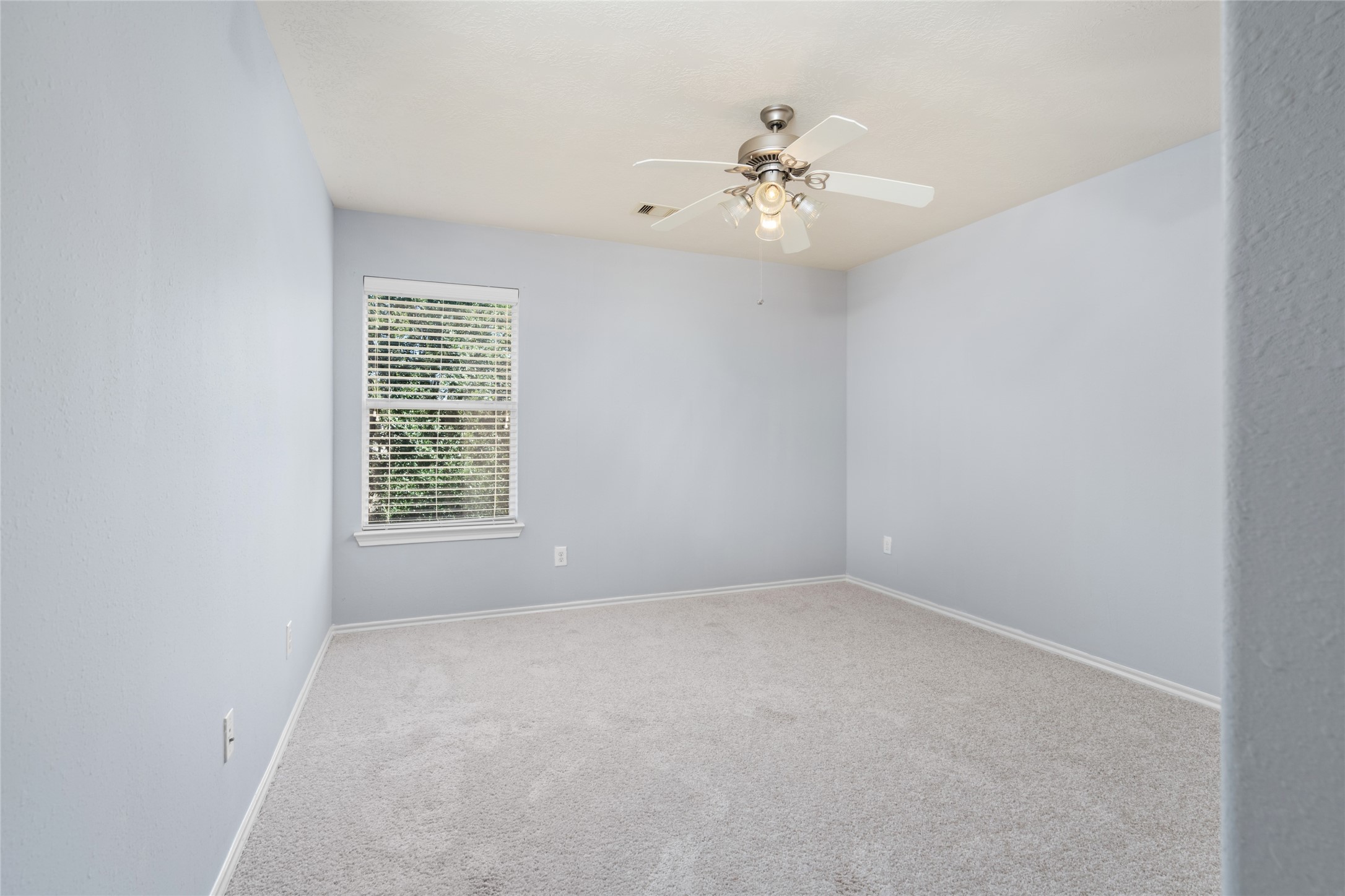 Unfurnished secondary bedroom with soft carpeting, a window, and neutral finishes. The open layout provides flexibility for a bedroom, guest room, or personal retreat, depending on the buyer's needs.