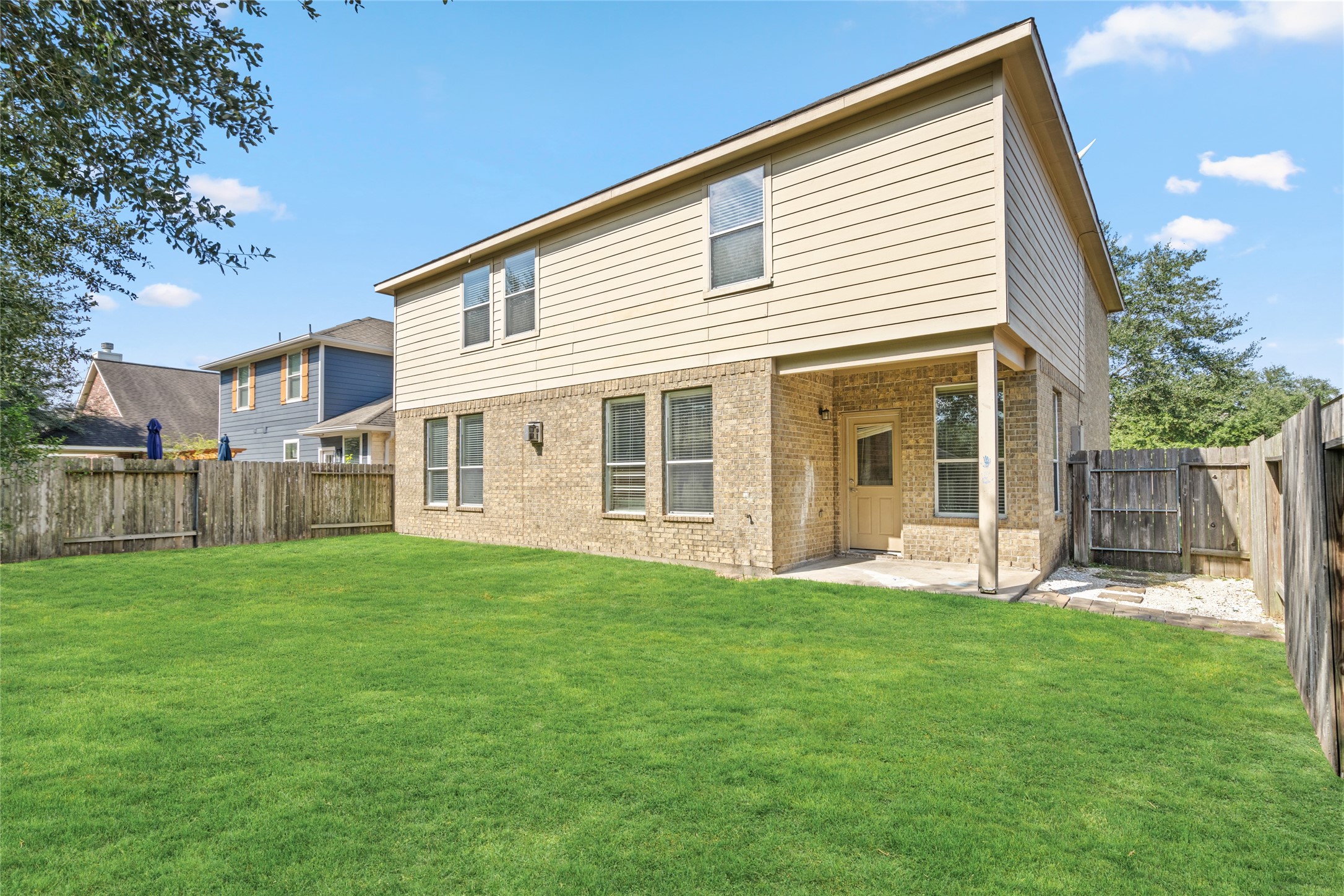 Rear exterior view of the two-story home, highlighting the brick-and-siding faade, multiple windows, and expansive lawn. The view illustrates the home's backyard setting and the outdoor space available for everyday enjoyment.