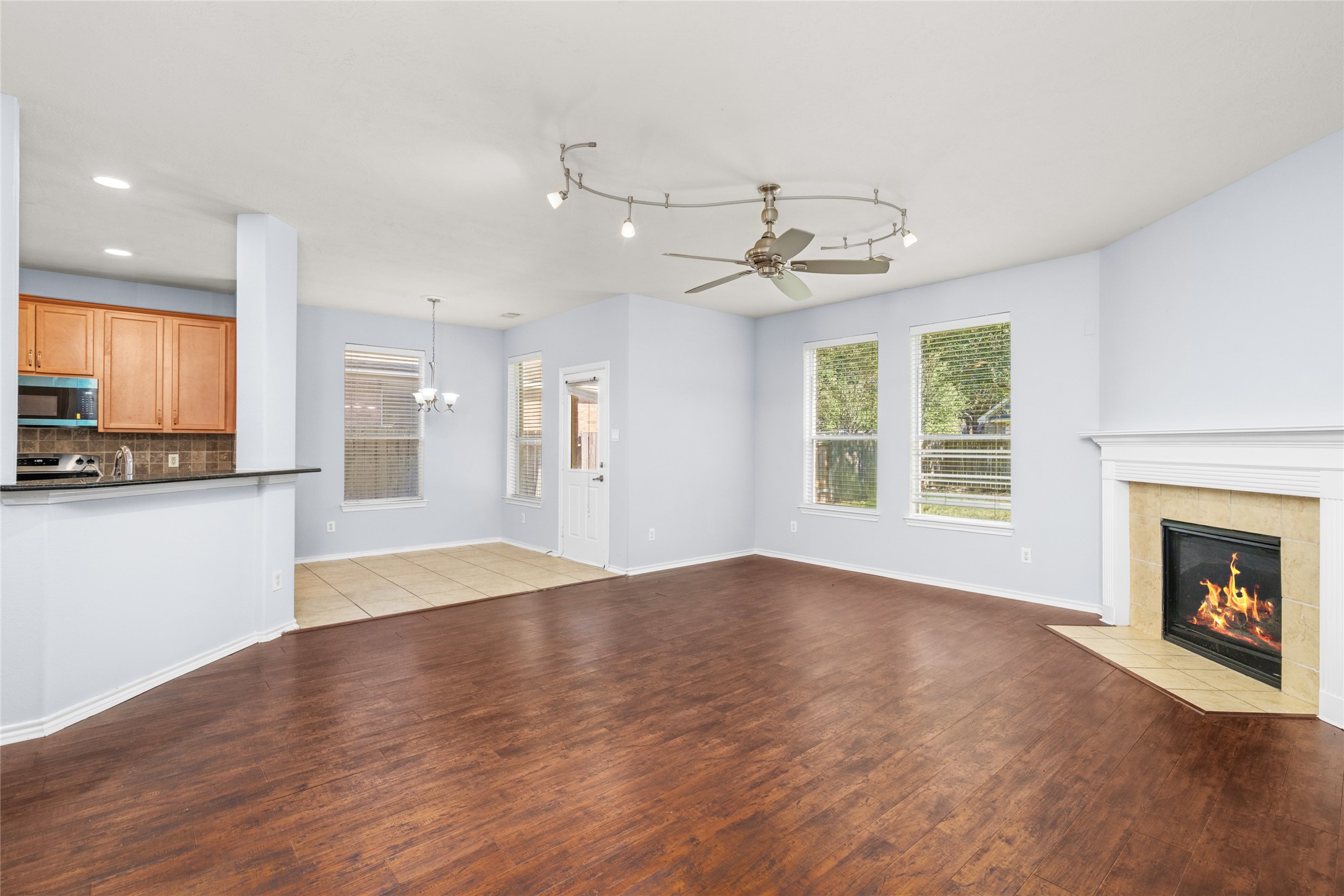 Open-concept living area with wood flooring, a corner fireplace, and a broad view toward the kitchen and breakfast area. The connected layout supports easy conversation and movement between the home's main gathering spaces.