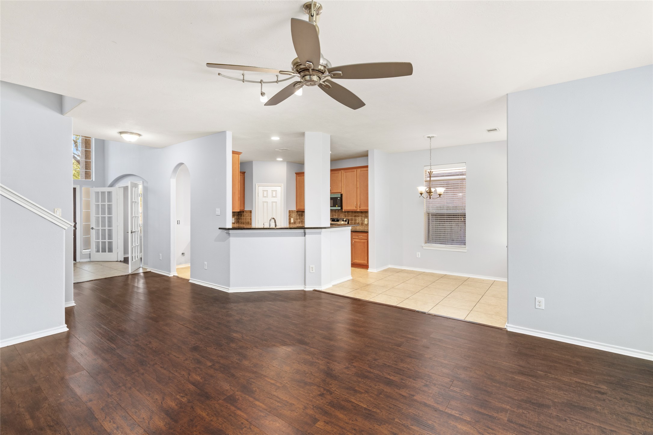 Wide view of the open living and dining areas, showcasing the continuous wood flooring and direct connection to the kitchen. The open sightlines make it easier to stay connected with family or guests while preparing meals or relaxing.