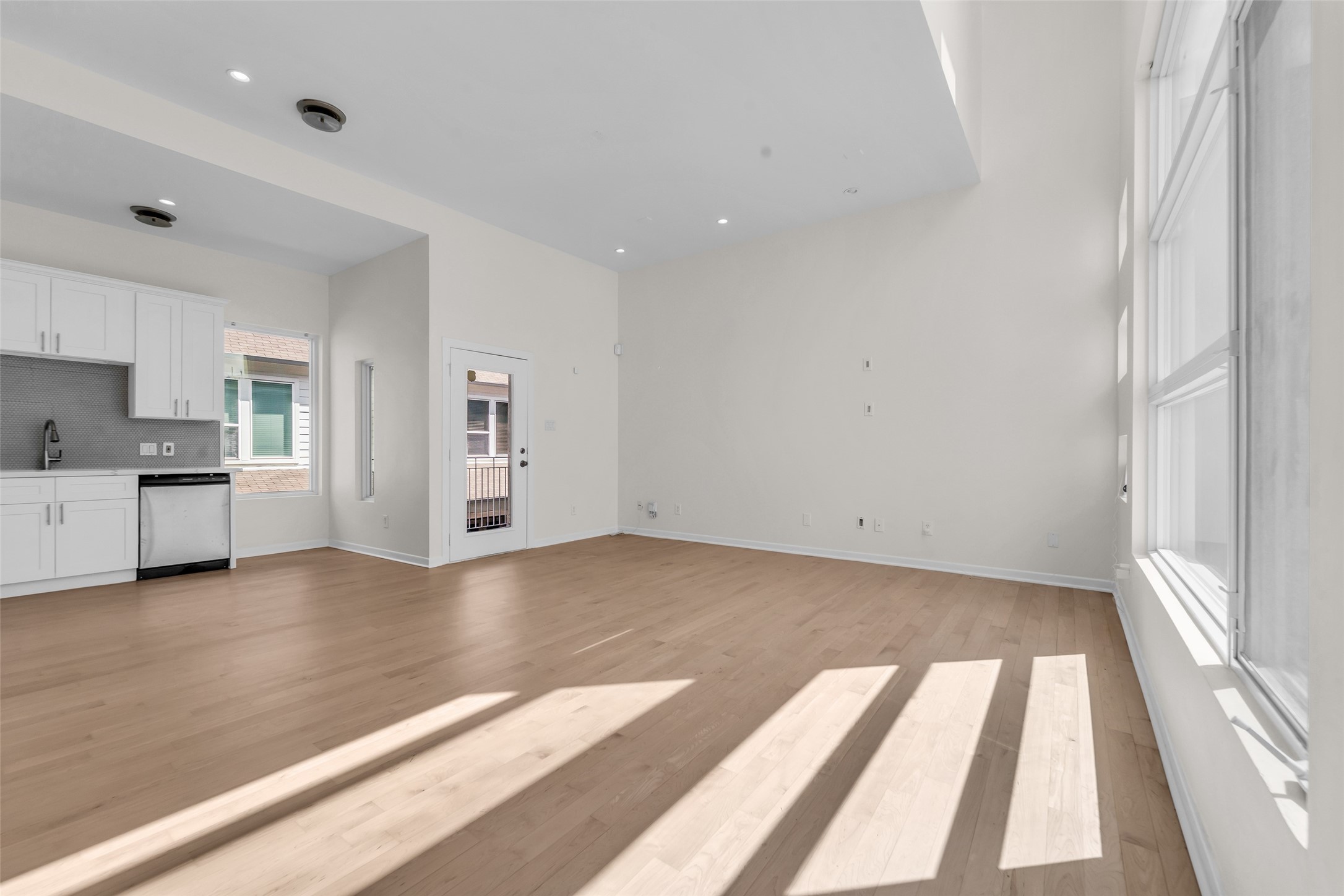Spacious open-concept living area with high ceilings, abundant natural light, and a modern brand new kitchen featuring new cabinetry and stainless steel appliances.