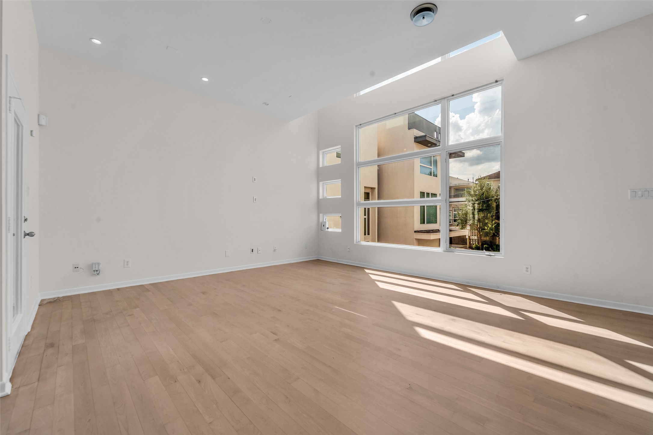 Spacious living area with high ceilings and large windows, offering abundant natural light and a modern, airy feel.