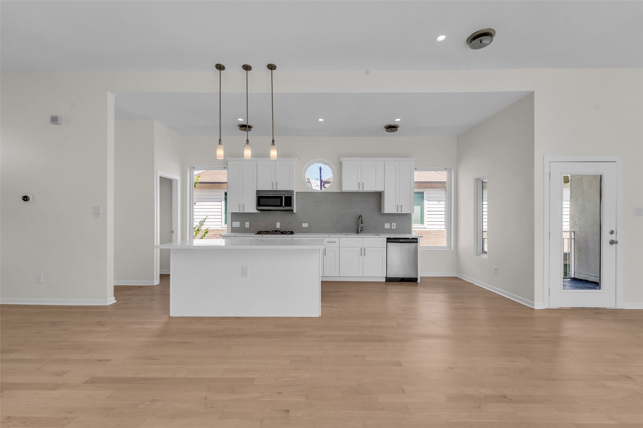 Spacious open-concept kitchen with sleek white cabinetry, stainless steel appliances, and modern pendant lighting over a central island.