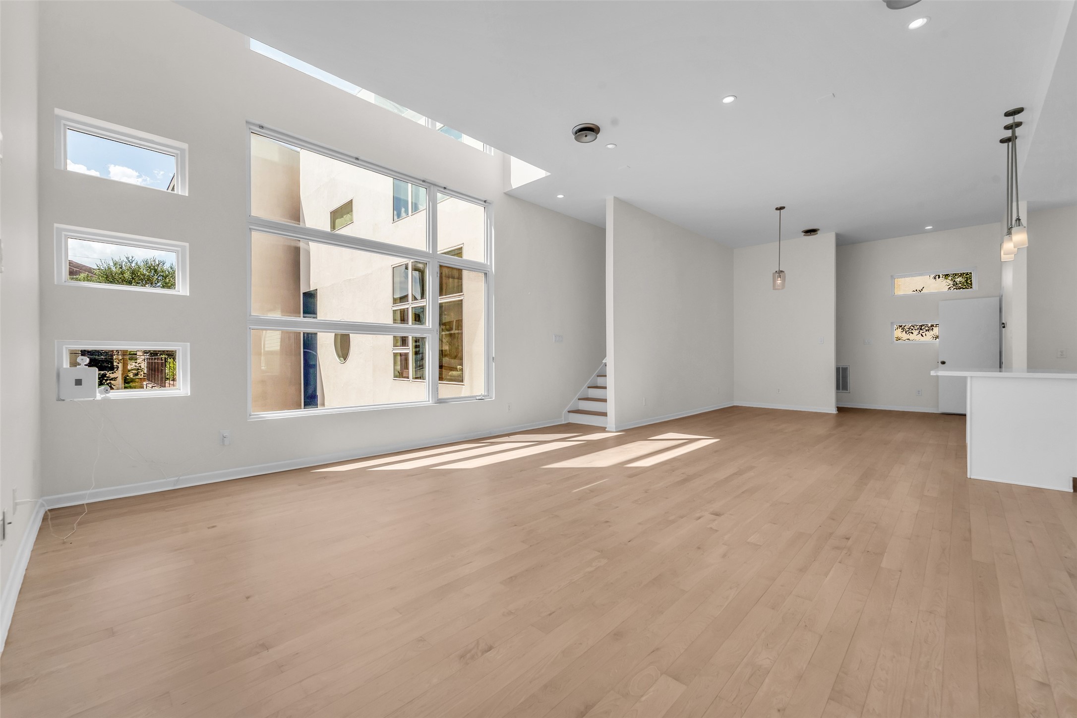 Bright and spacious open-concept living area featuring high ceilings, expansive windows, and modern finishes, perfect for entertaining and relaxation.
