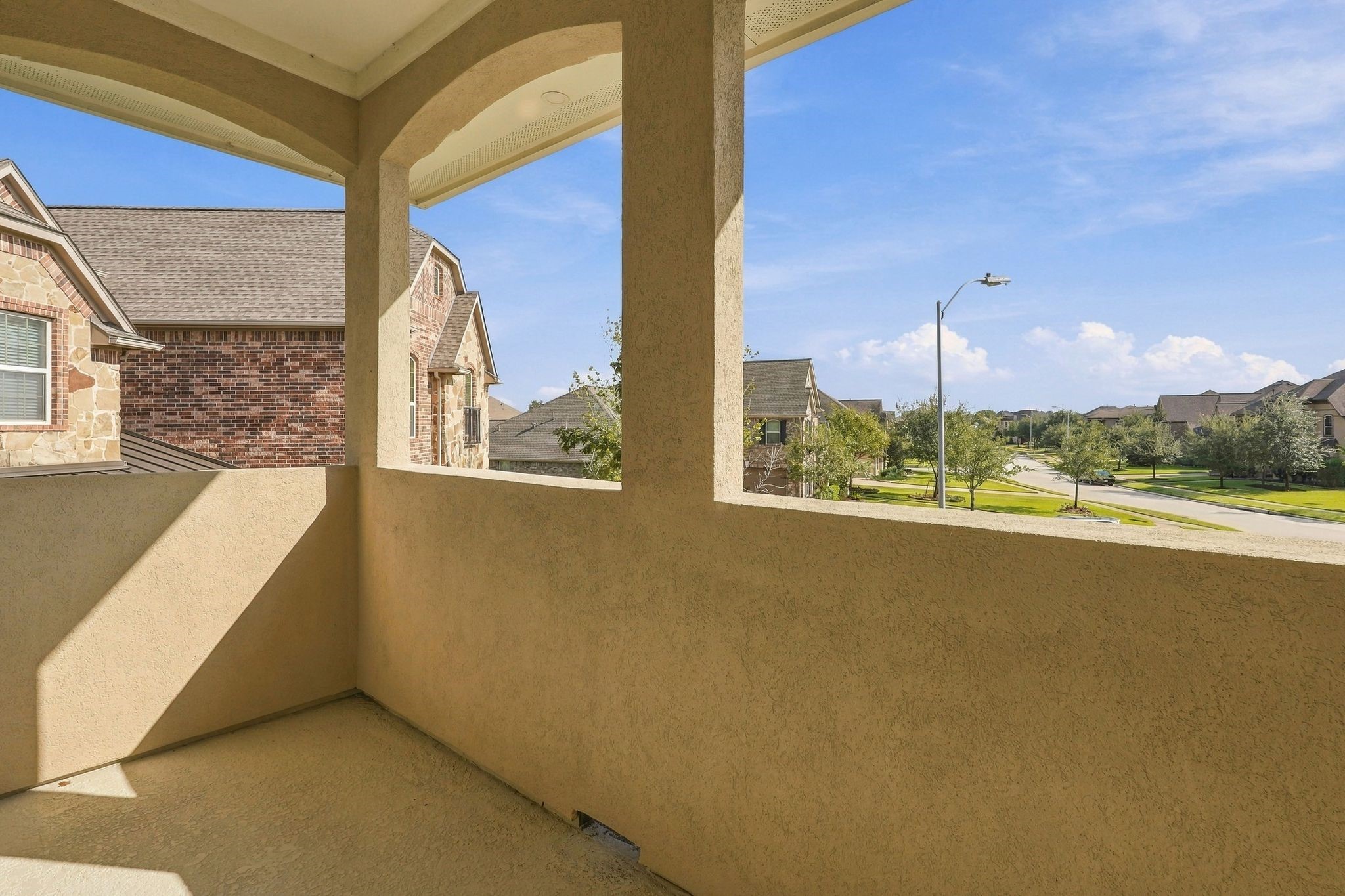 Charming second-story covered balcony featuring elegant arched architectural details and elevated views of the beautifully maintained Wildwood at Northpointe neighborhood. A wonderful outdoor retreat to enjoy fresh air and peaceful neighborhood views.