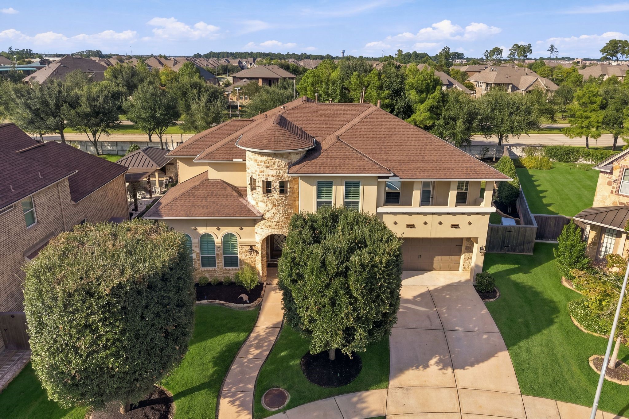 Impressive aerial view showcases this beautifully maintained luxury home in the gated Wildwood at Northpointe community. Distinctive stone turret, elegant architectural details, manicured landscaping, and a spacious driveway complement the home's exceptional curb appeal. Recent upgrades include a 2025 Class 4 impact-resistant roof!
