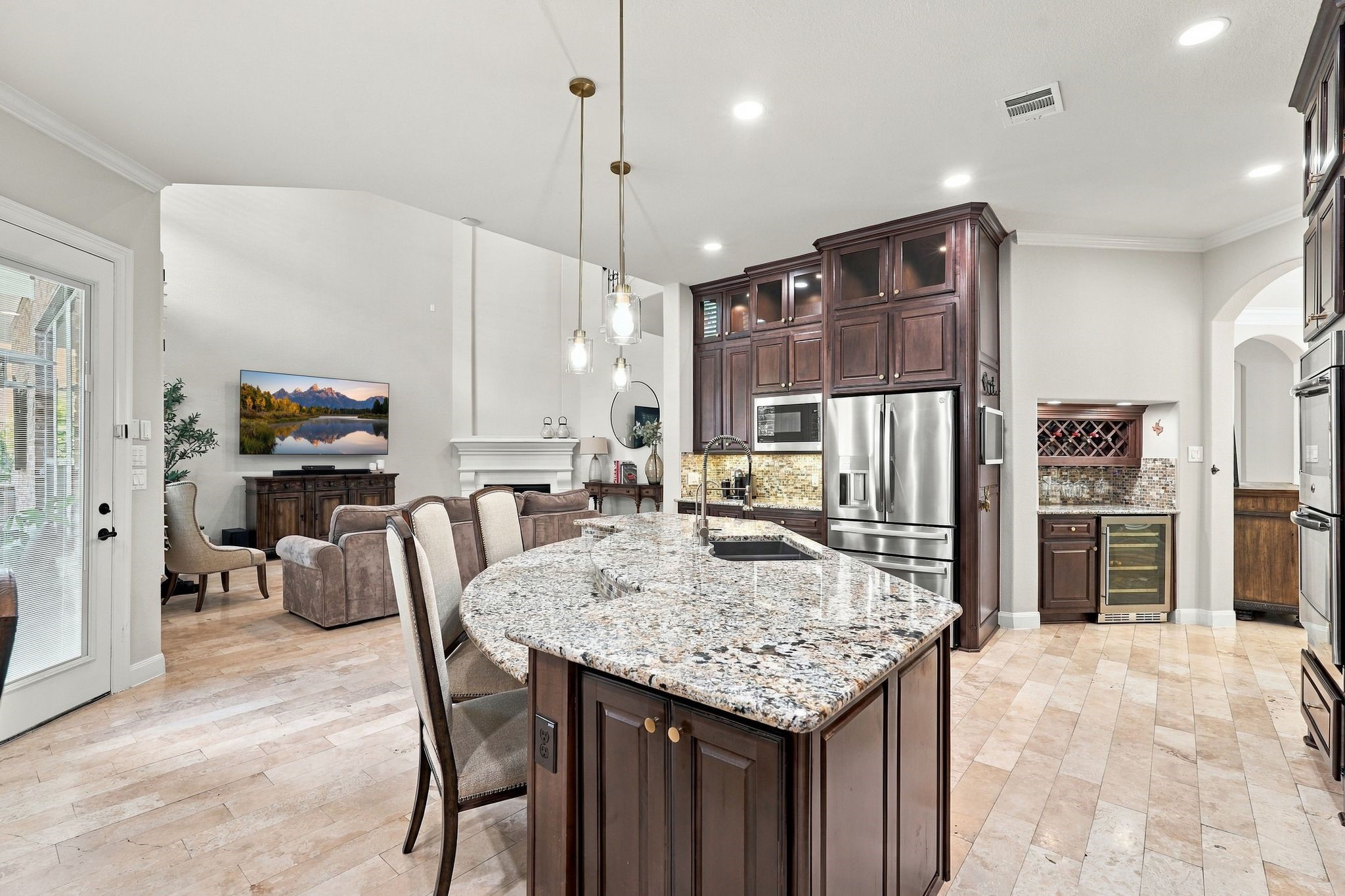 Designed for elevated living and effortless entertaining, this exceptional gourmet kitchen showcases an expansive granite island, rich custom cabinetry, stainless steel appliances, and elegant pendant lighting. The open-concept design flows beautifully into the grand two-story living room, while a dedicated wine bar with built-in wine chiller adds a touch of luxury and sophistication.