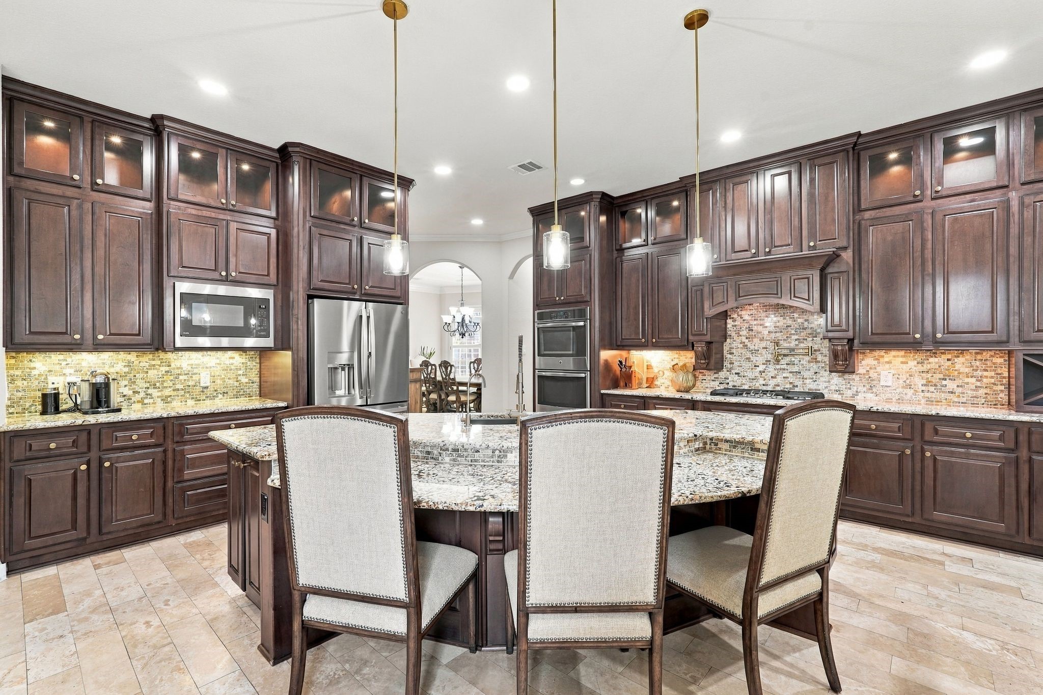 The showstopping centerpiece of this gourmet kitchen is the expansive granite island, featuring a beautiful multi-level design, generous breakfast bar seating, and an integrated sink. Elegant pendant lighting highlights this impressive space, perfect for meal preparation, casual dining, and effortless entertaining.
