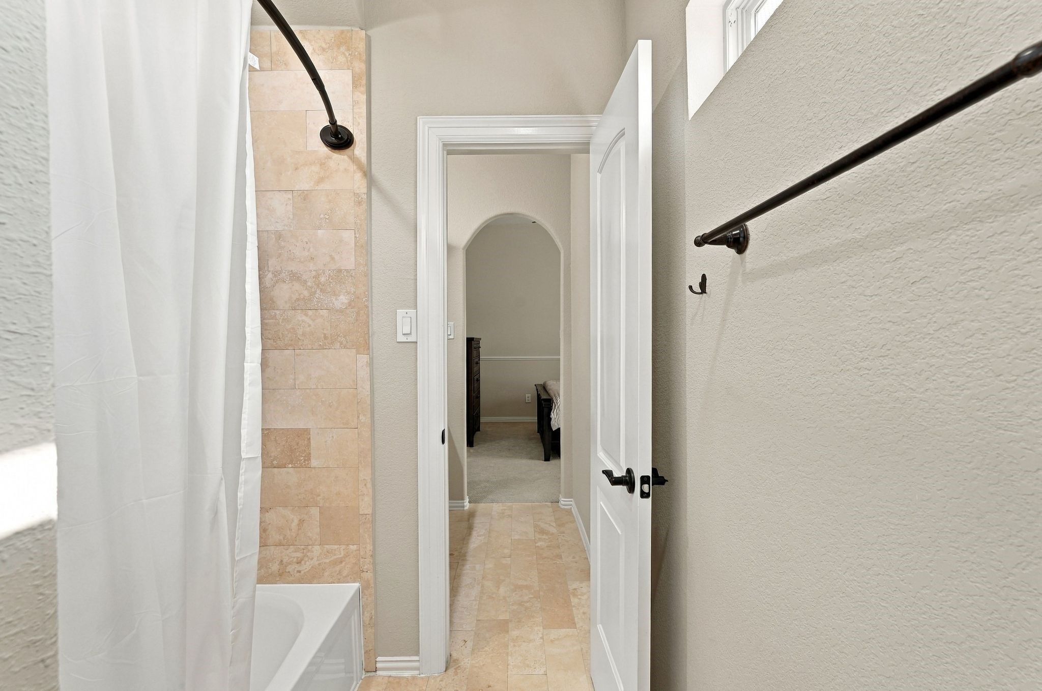 Jack-and-Jill bathroom features a shared tub and shower combination with beautiful natural stone tile surround, coordinating tile flooring, and access to adjoining bedrooms. A functional design offering comfort and privacy.