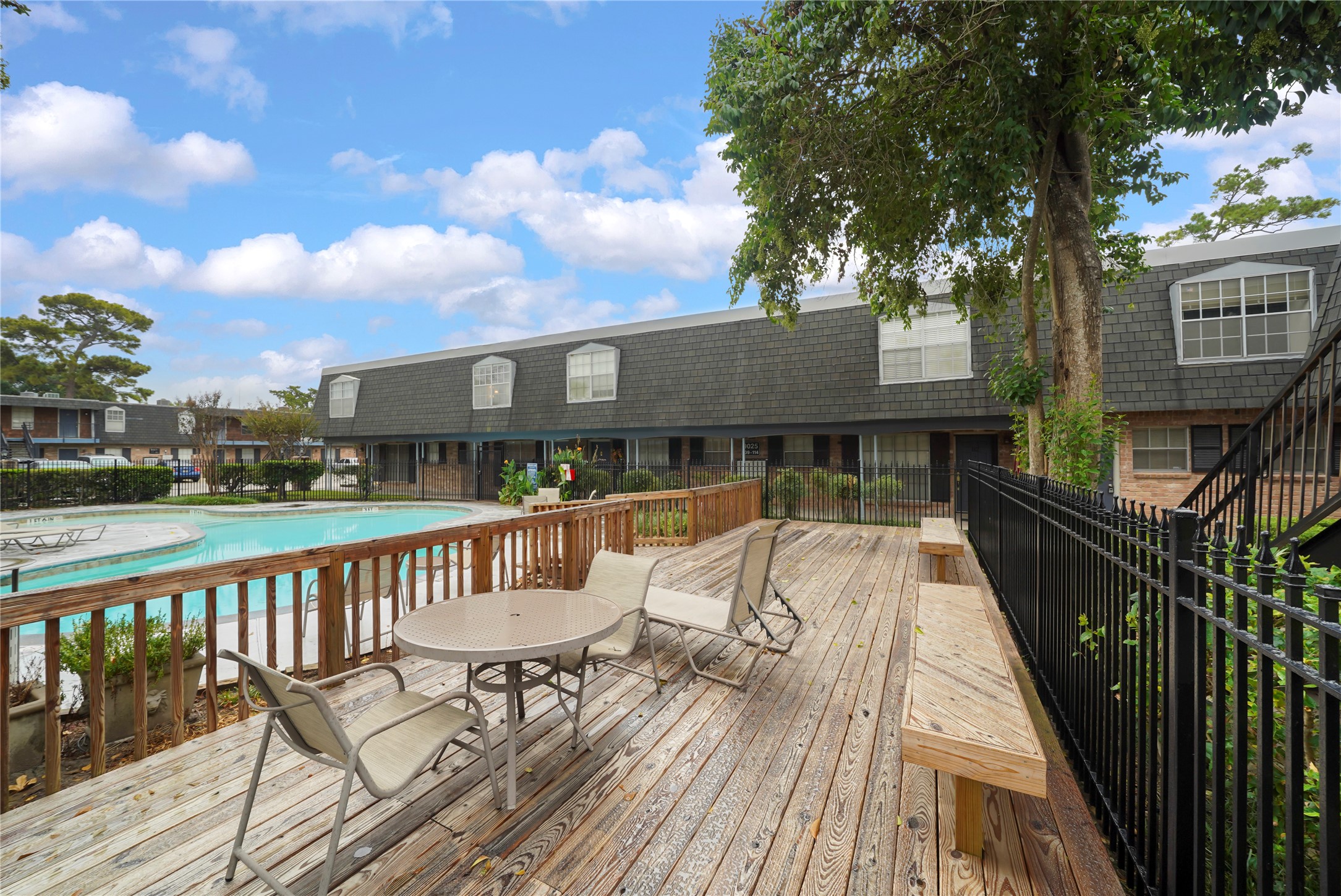 Wooden sun deck and patio area adjacent to the pool, complete with table seating and lounge chairs for outdoor entertaining.