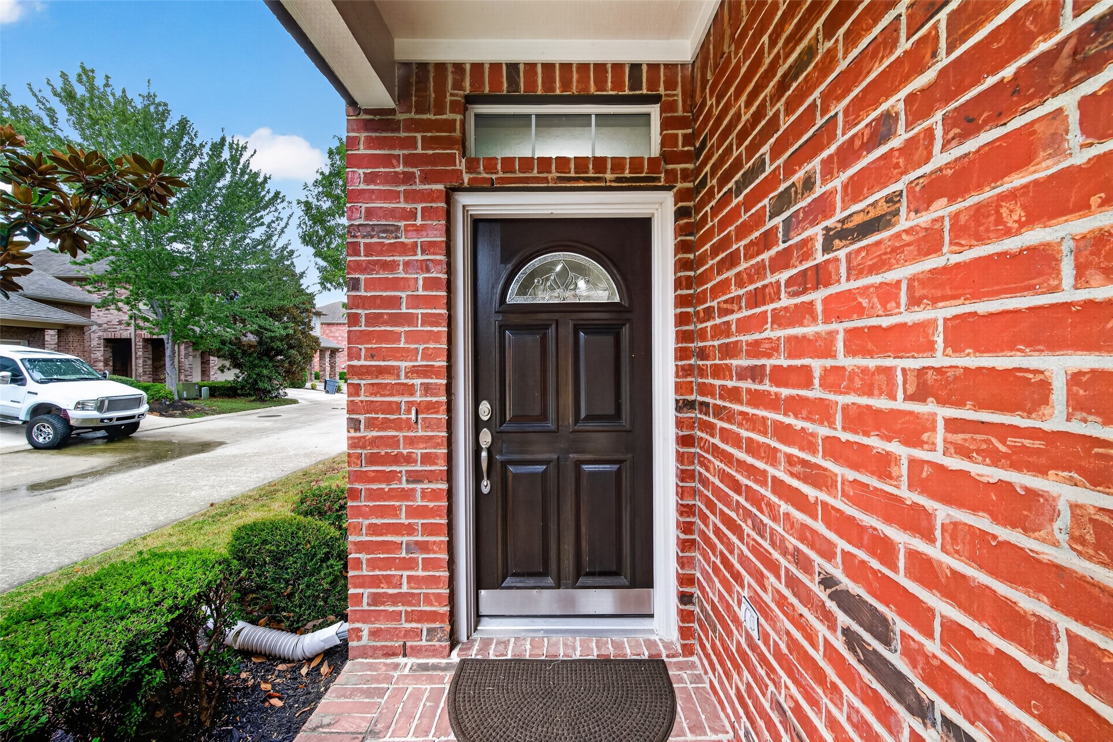 Charming red brick patio with transom window above a wood and leaded glass door welcomes guests.
