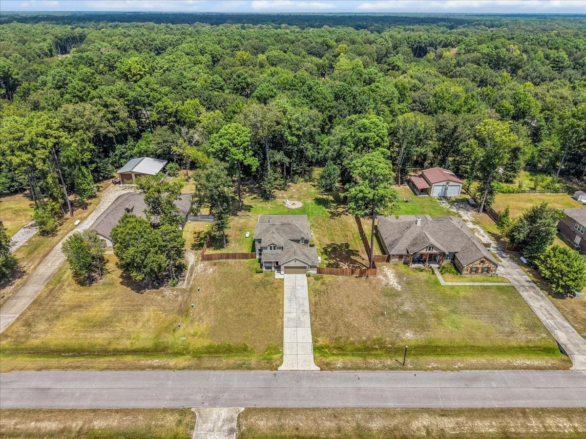 Aerial view showcases the home's generous lot, spacious surroundings and beautiful wooded setting.