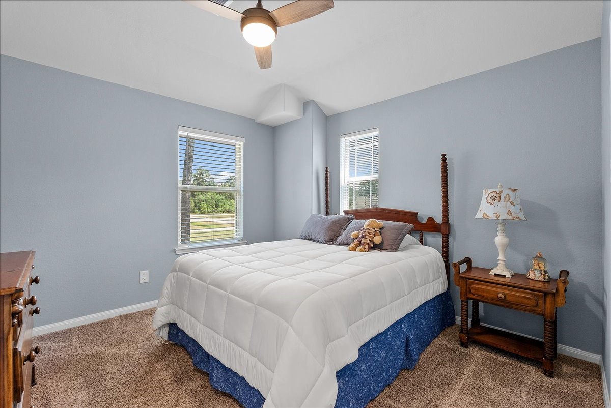 Bright secondary bedroom offers comfortable carpet, a ceiling fan and plenty of natural light.
