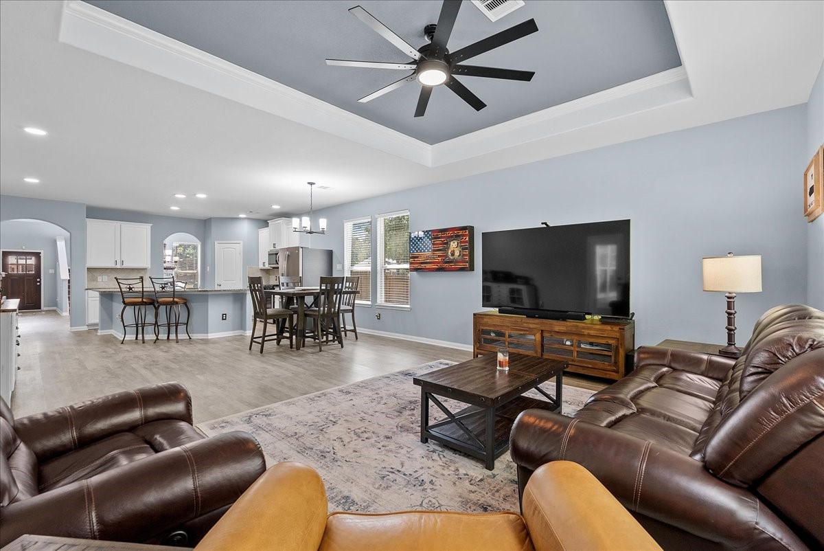Another view of the open living space showcases the beautiful tray ceiling and easy flow into the kitchen and dining areas.
