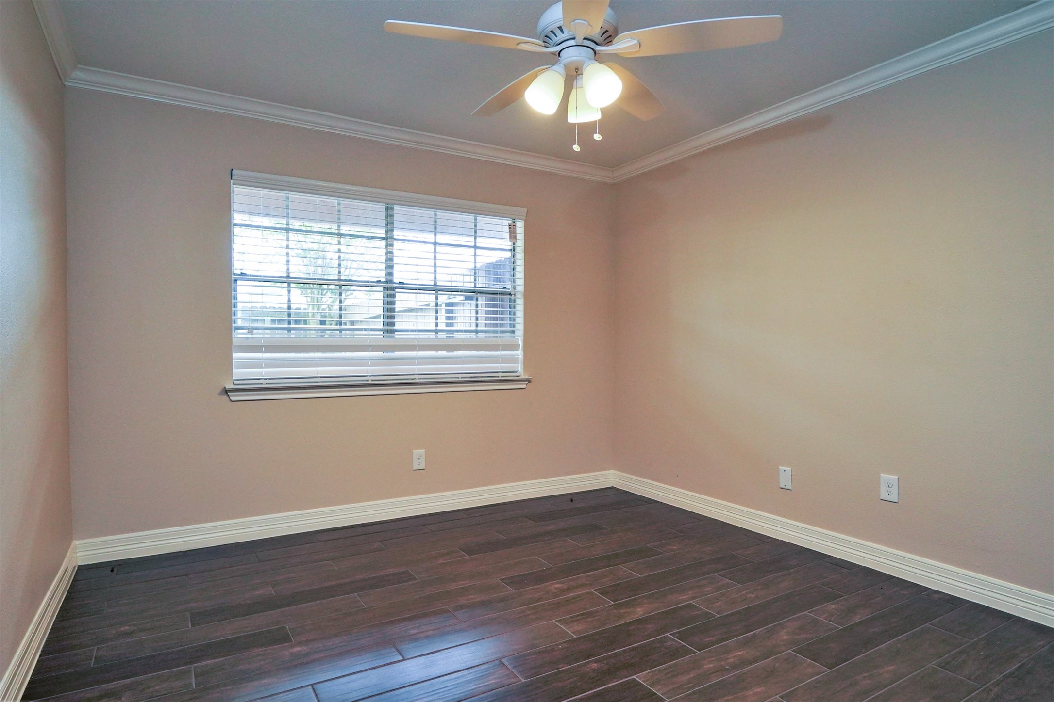 Primary bedroom with tile "like hardwood floors, ceiling fan, crown molding, window overlooks back patio