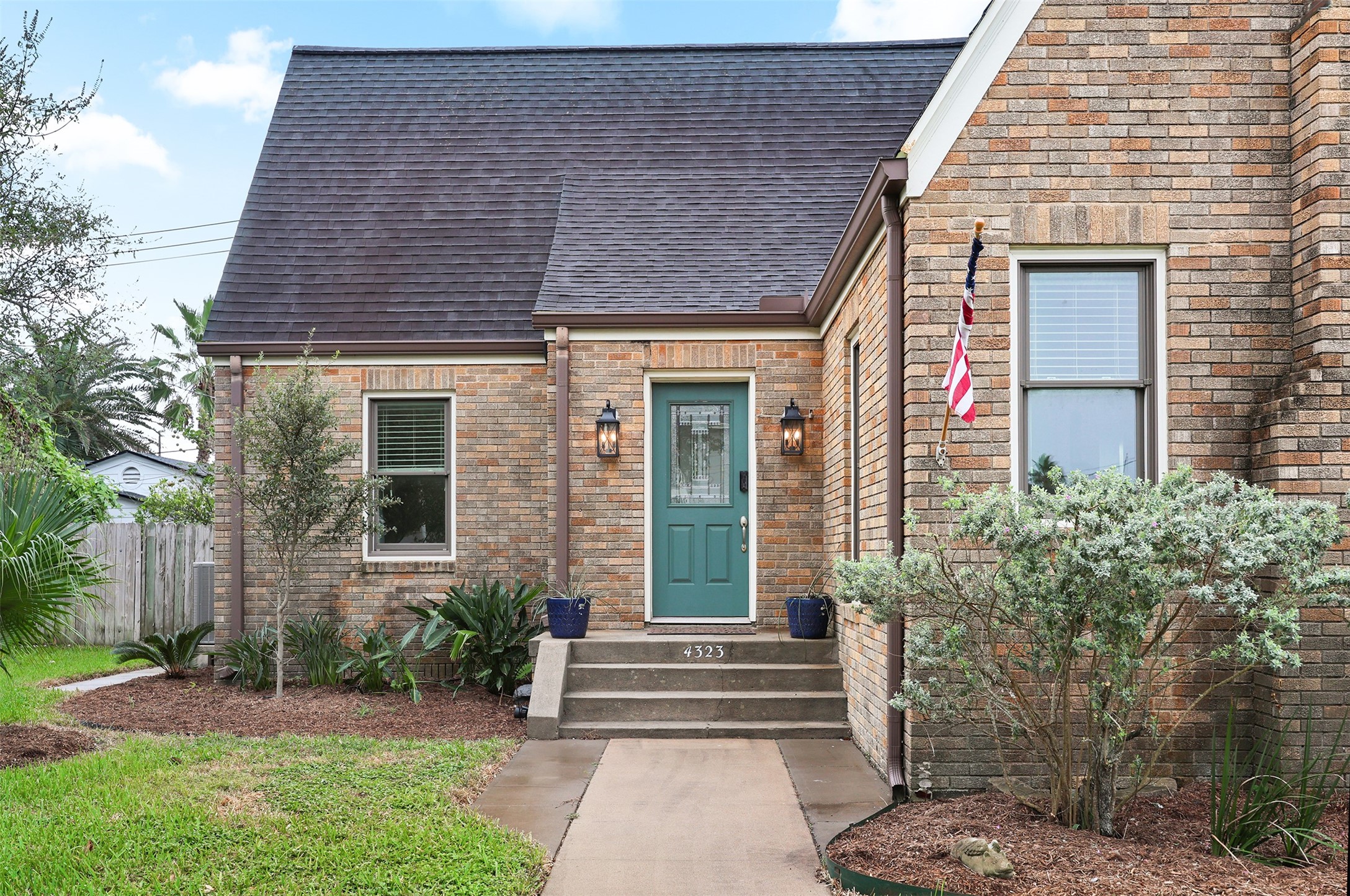 Welcoming green front door, flanked by classic lantern-style lights.