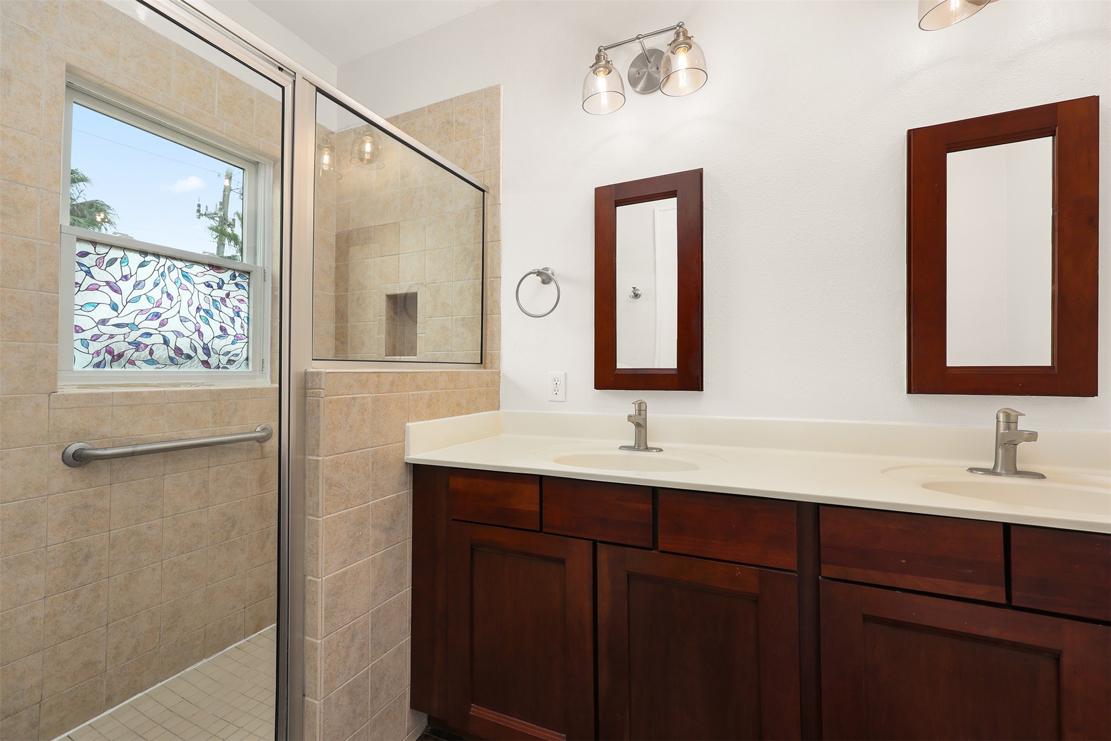 Ensuite bathroom featuring a dual-sink vanity with spacious glass-enclosed shower.
