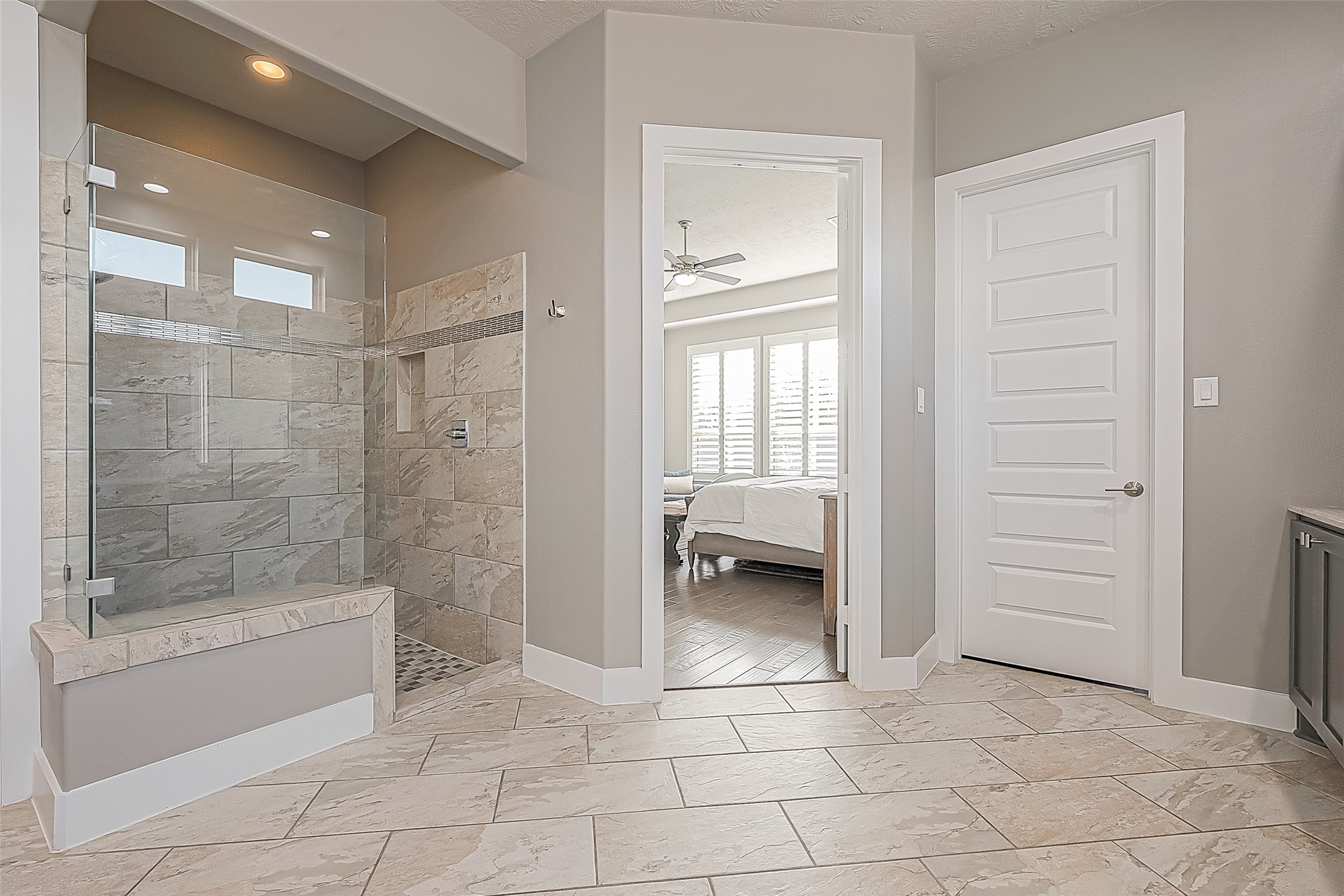 The stunning primary shower has decorative tiles and a frameless shower door.