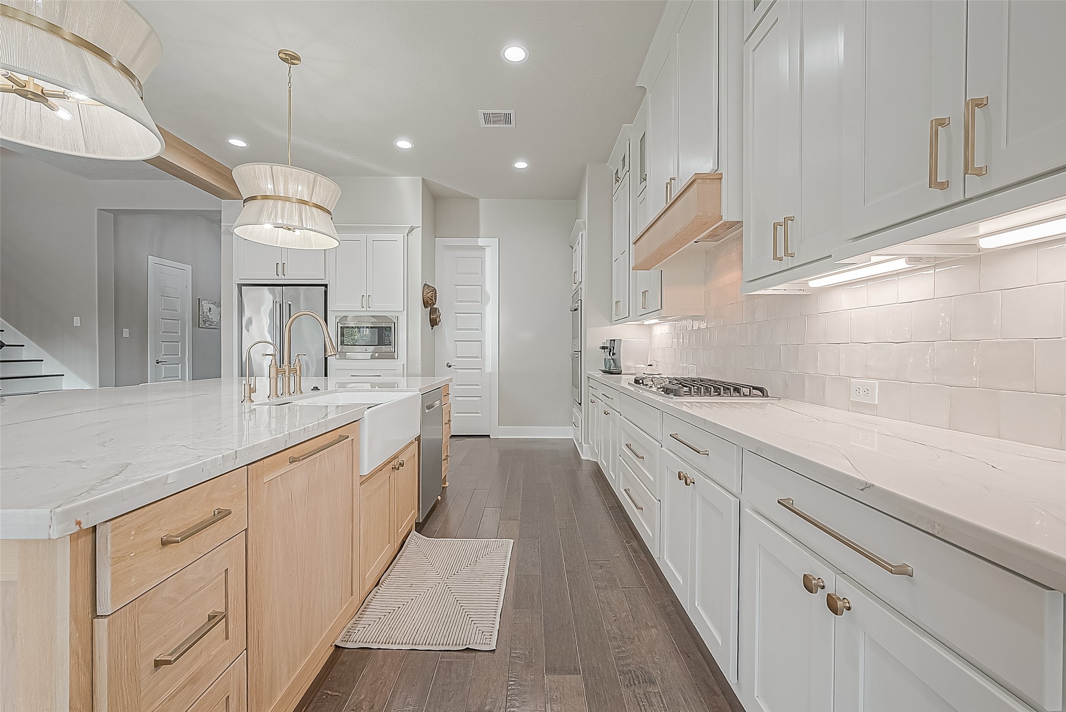 The cabinets are adorned with elegant gold accents, complementing the custom lighting fixtures with a luxury feel.