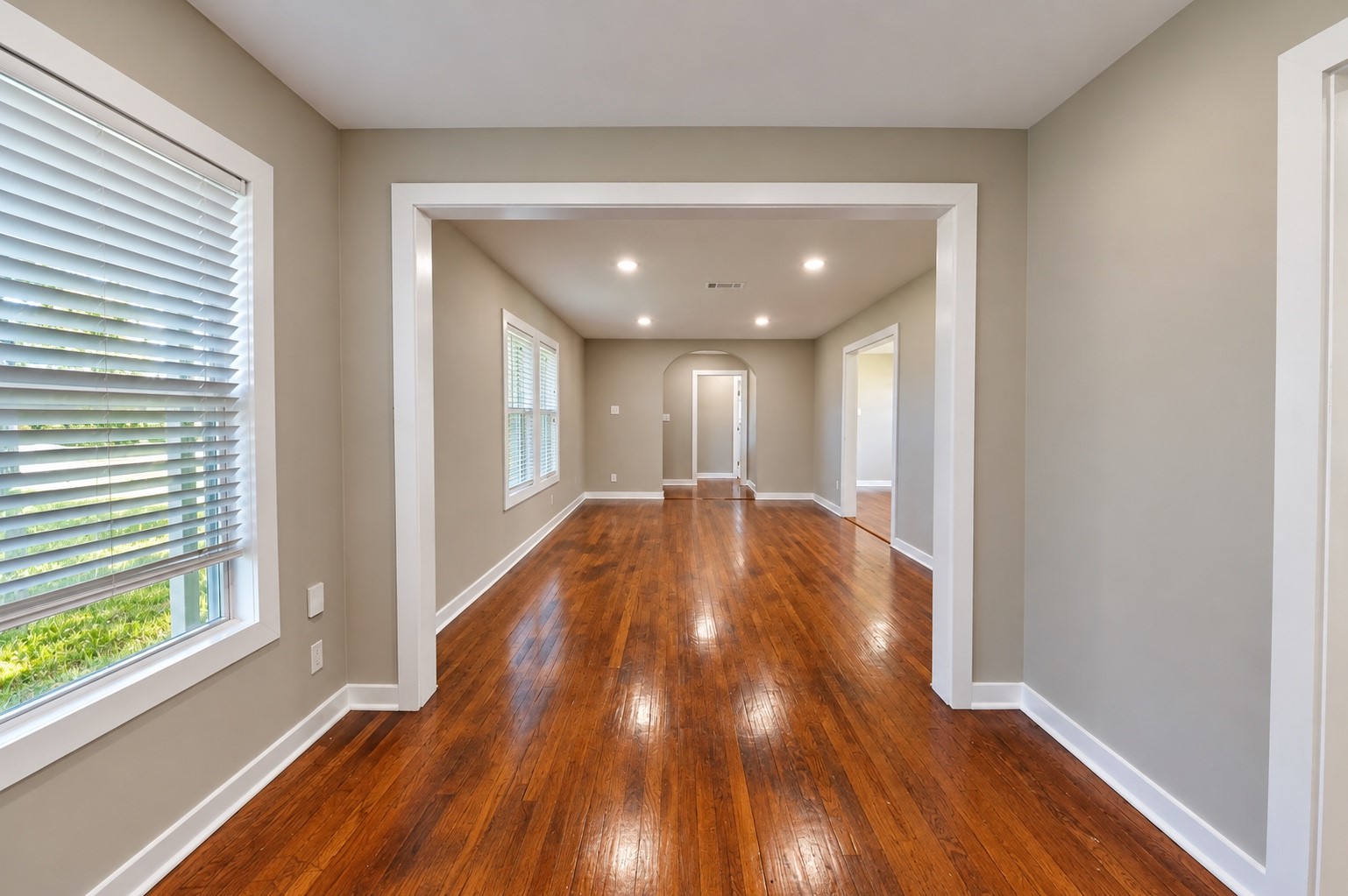 Bright, open living space with gleaming hardwood floors and large windows that invite natural light.