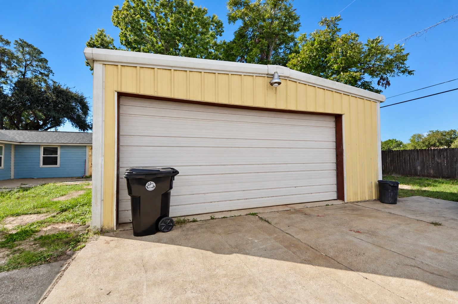 Spacious detached garage with a wide door, set on a concrete driveway, perfect for storage or parking.