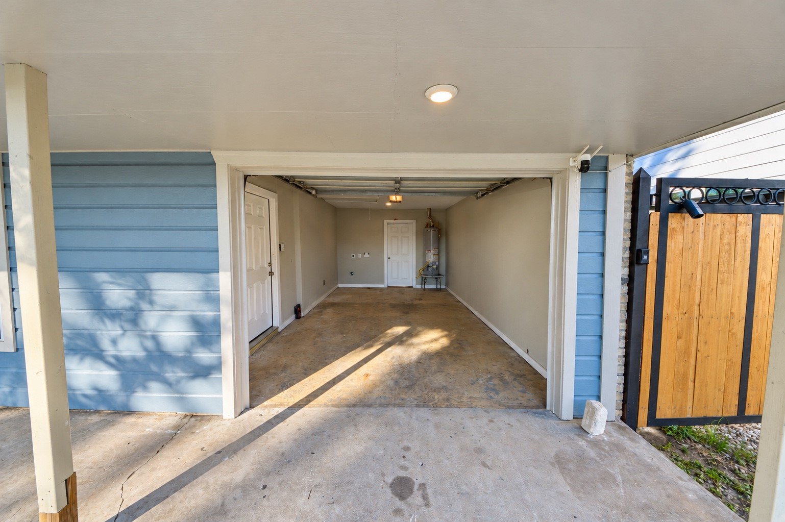 A spacious garage with clean lines and ample lighting, featuring a secure wooden gate and convenient interior access.