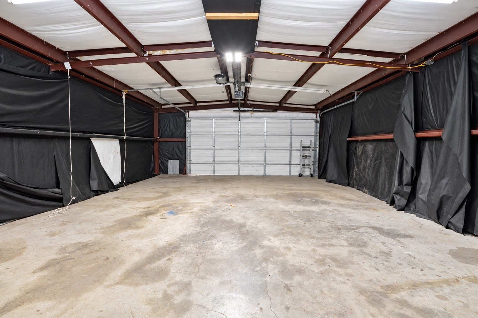 Spacious garage with high ceilings and ample room for vehicles or storage, featuring a large roll-up door for easy access.