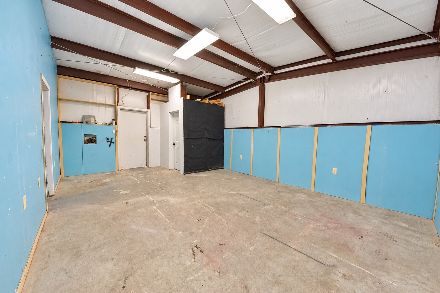 Spacious utility room with exposed beams and ample lighting, offering versatile potential for customization and convenient half bath