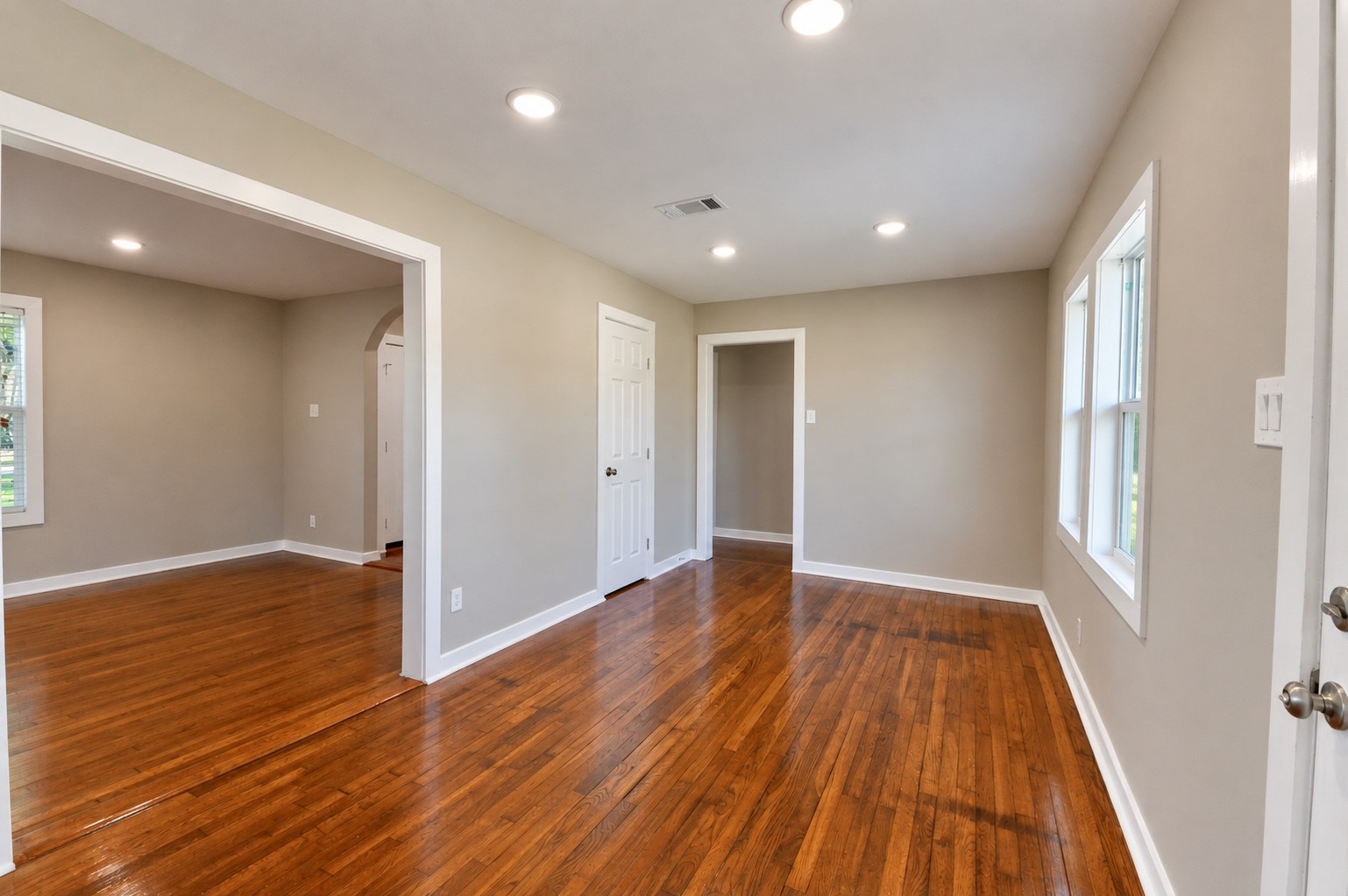 Bright and inviting living area with gleaming hardwood floors, recessed lighting, and neutral walls, creating a warm and welcoming atmosphere.