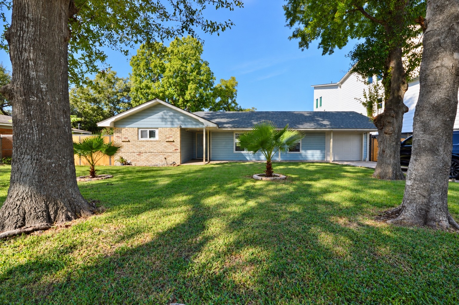 Charming single-story home with a spacious front yard, mature trees, and a cozy brick and siding exterior.