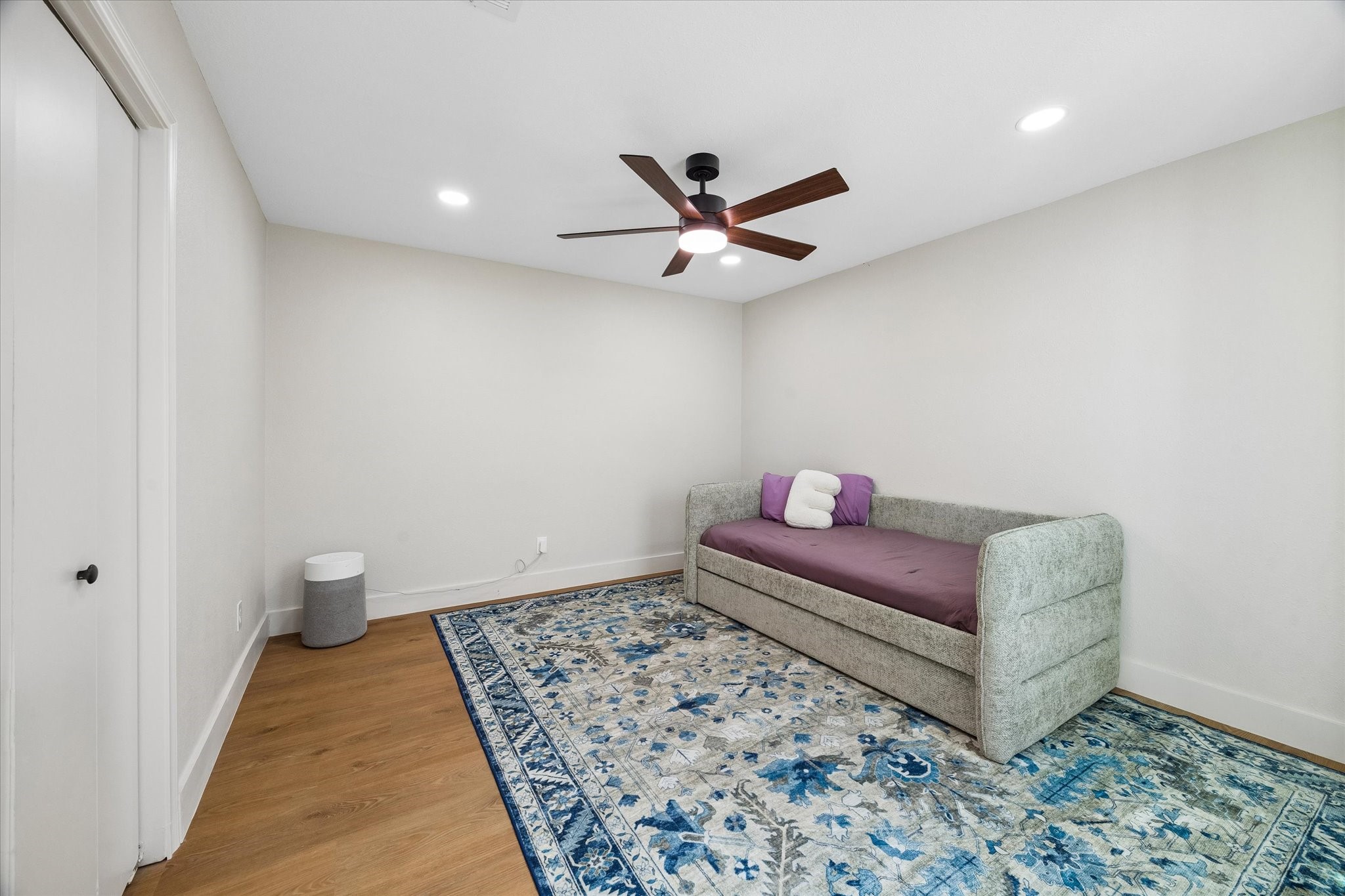 This cozy secondary bedroom with a modern ceiling fan is the perfect place for relaxation or a guest retreat.