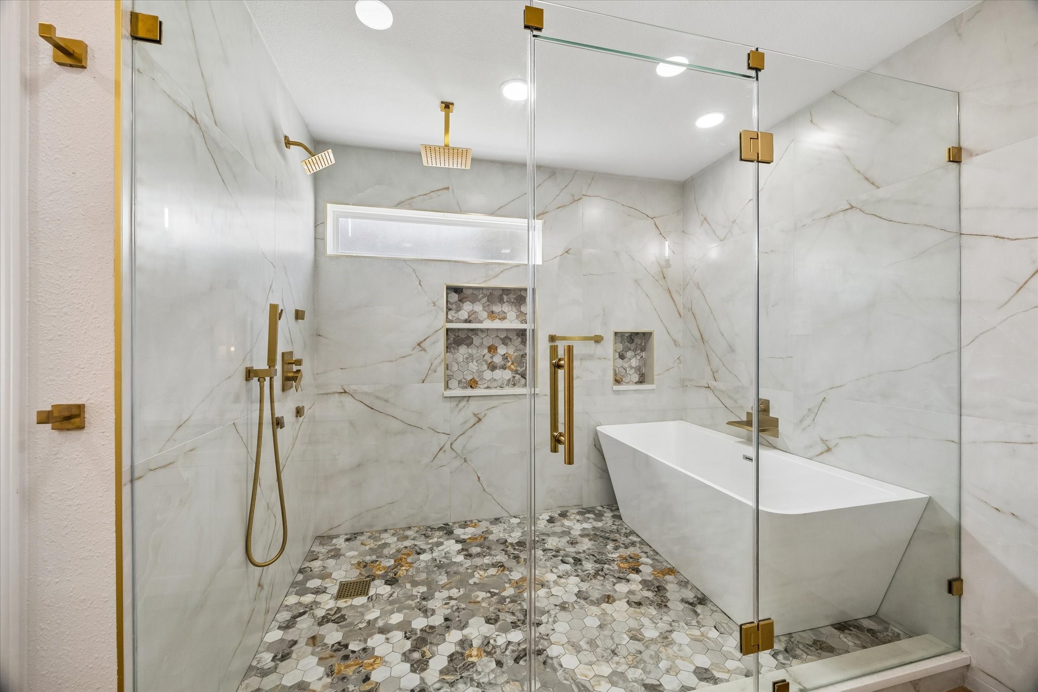 Luxurious bathroom featuring a spacious glass-enclosed shower with dual rain showerheads, elegant walls, and a modern freestanding tub.