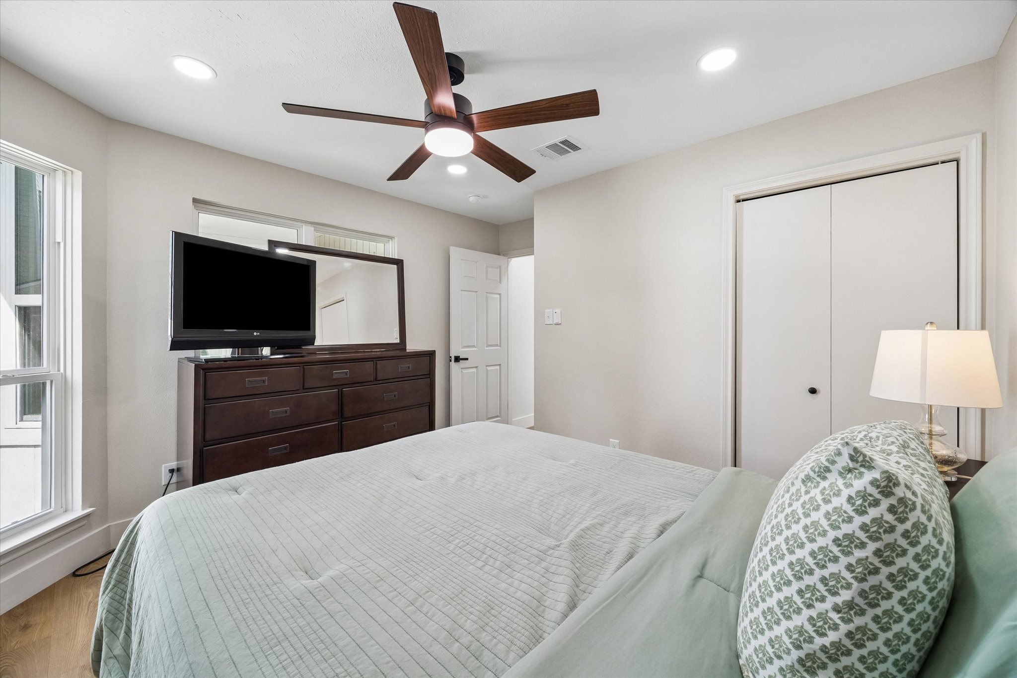 Elegant secondary bedroom featuring a spacious layout with a large window for natural light, modern ceiling fan, and ample storage.