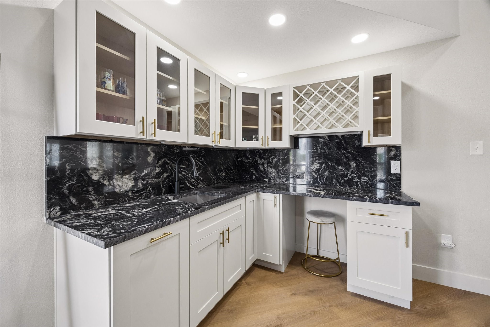 This elegant wet bar flows into the living room  area and features sleek black countertops, white cabinetry with glass doors, and a built-in wine rack.  It is perfect for entertaining.