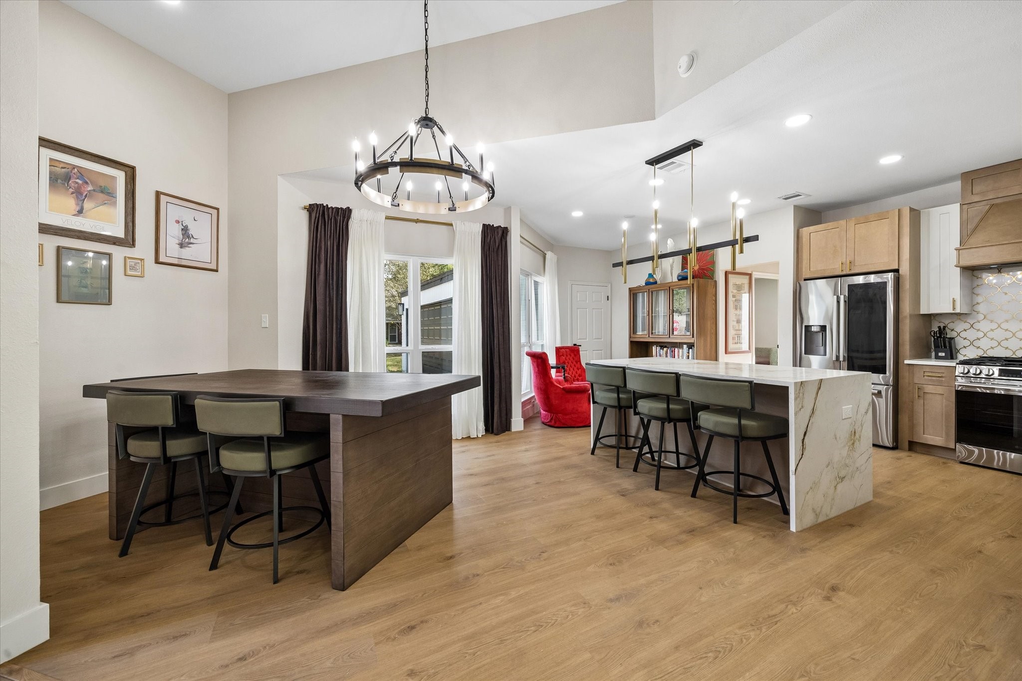 Spacious open-concept kitchen and dining area features a large island with elegant light fixtures, and a cozy dining nook with a view.