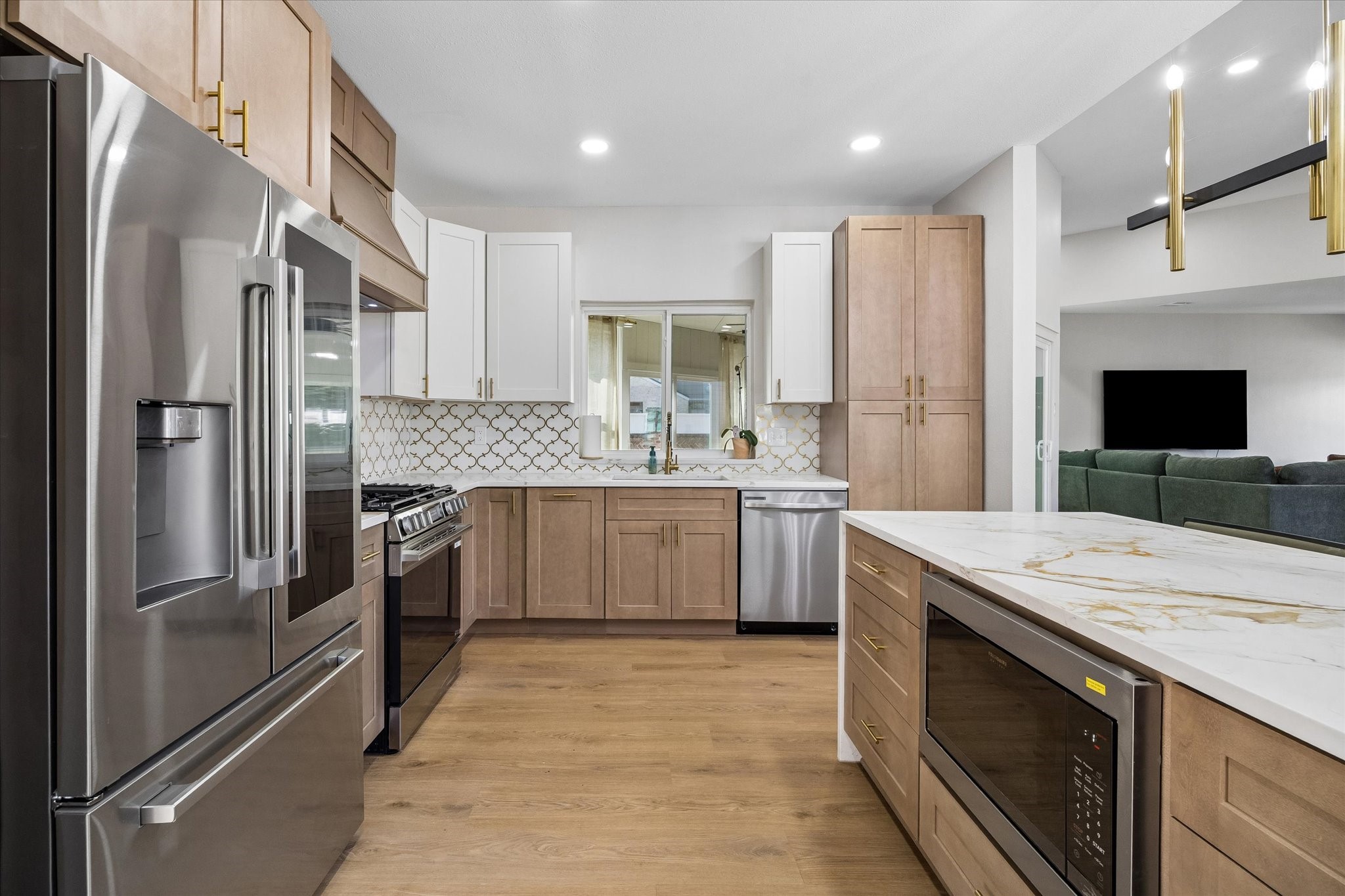 Modern kitchen with sleek stainless steel appliances, elegant light wood cabinetry, and a spacious island featuring a quartz countertop.