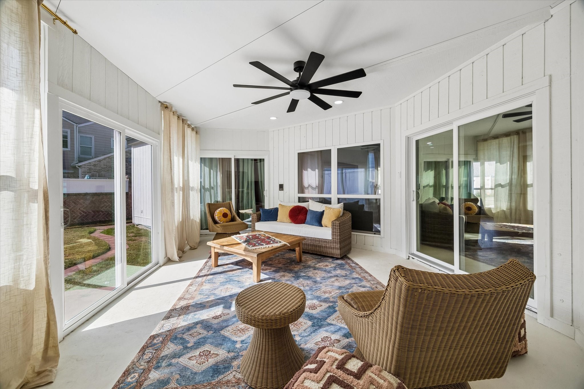 Bright and inviting enclosed sunroom featuring large windows, a stylish ceiling fan is perfect for relaxing and enjoying the view.