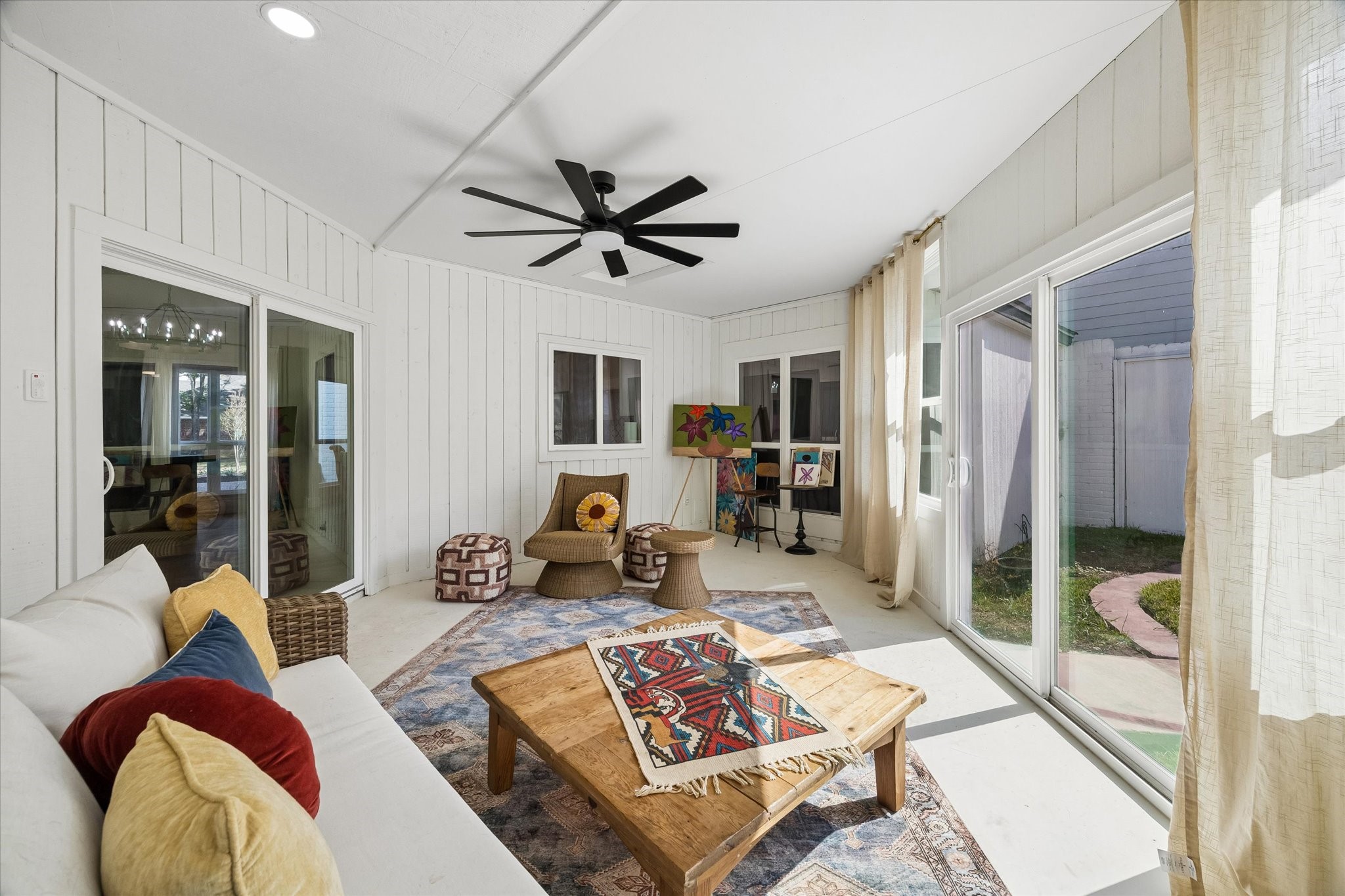 Bright and inviting sunroom featuring large windows, a modern ceiling fan is the perfect place for rest and relaxation.
