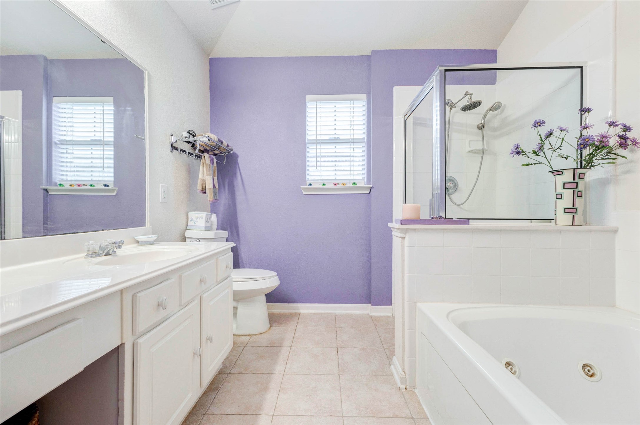 Generously sized primary bathroom with a combination of vanity, jetted tub, and separate shower area. The layout provides flexibility for daily routines, while natural light and soft color tones create a relaxing environment. A comfortable space designed for both convenience and everyday luxury.